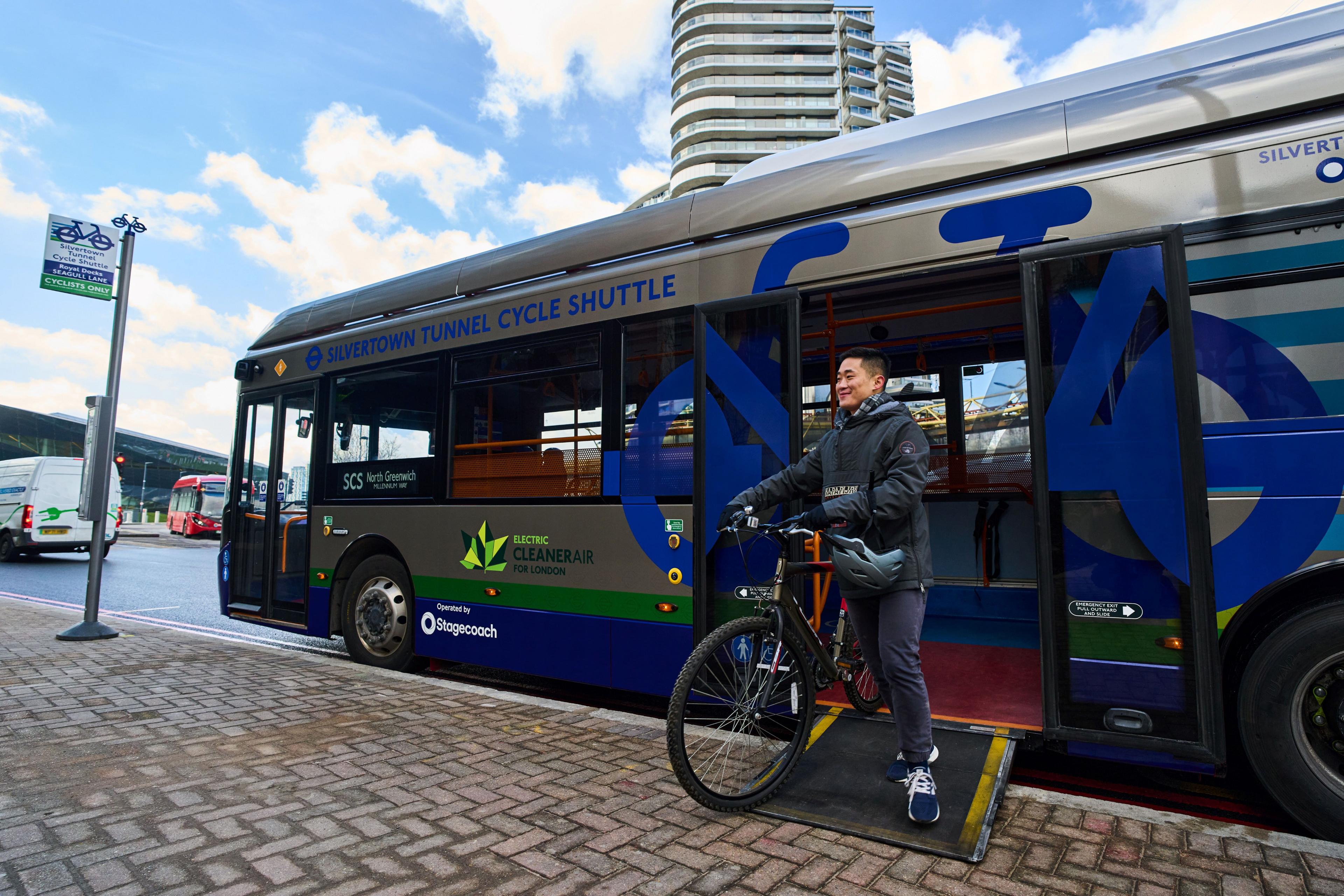 Man with bike uses ramp to disembark bus which says Silvertown Tunnel Cycle Shuttle