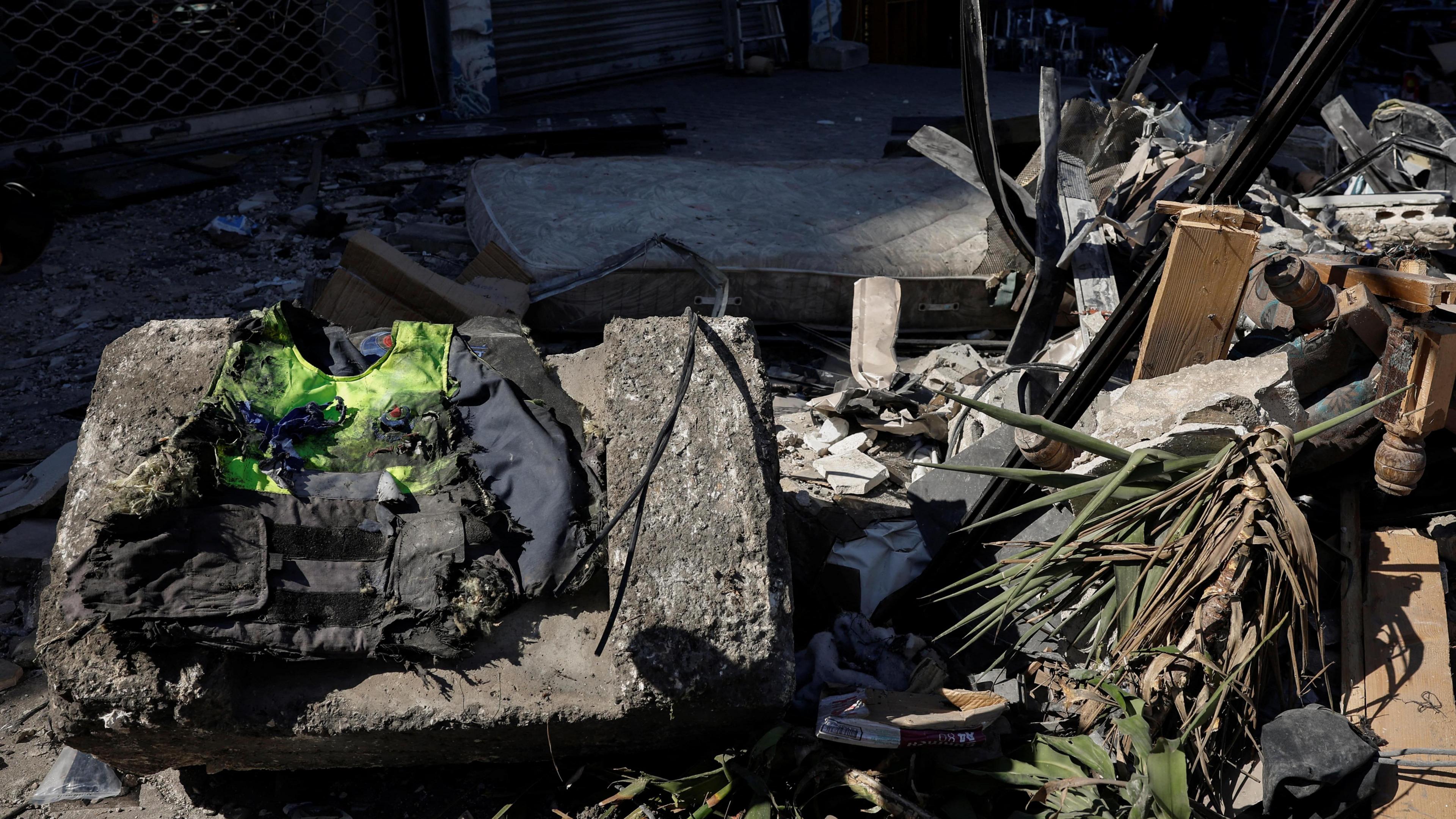 A burnt high-vis jacket on top of a fallen concrete block beside a pile of rubble.