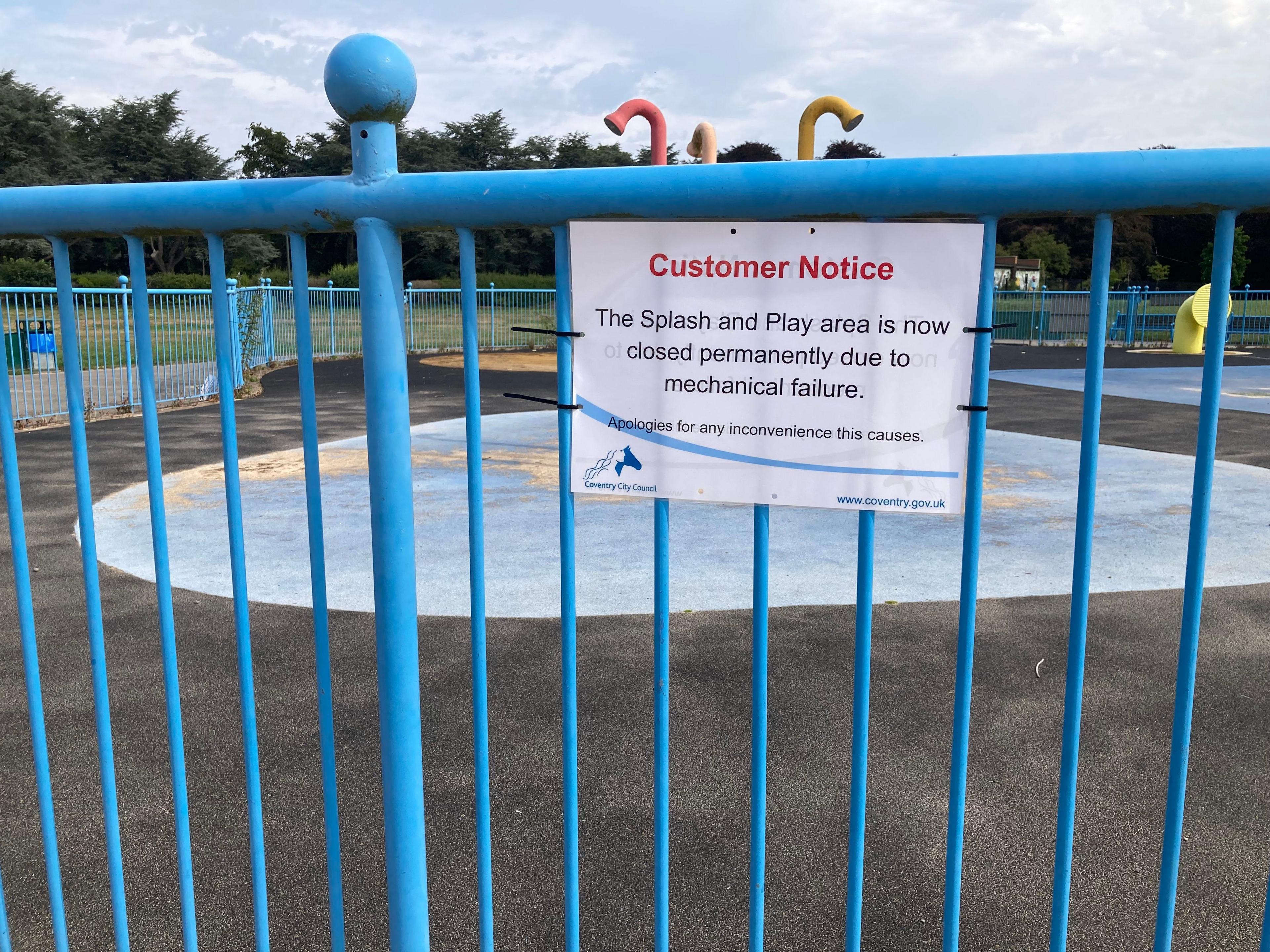 A sign hangs on the railings at the splash pad feature.