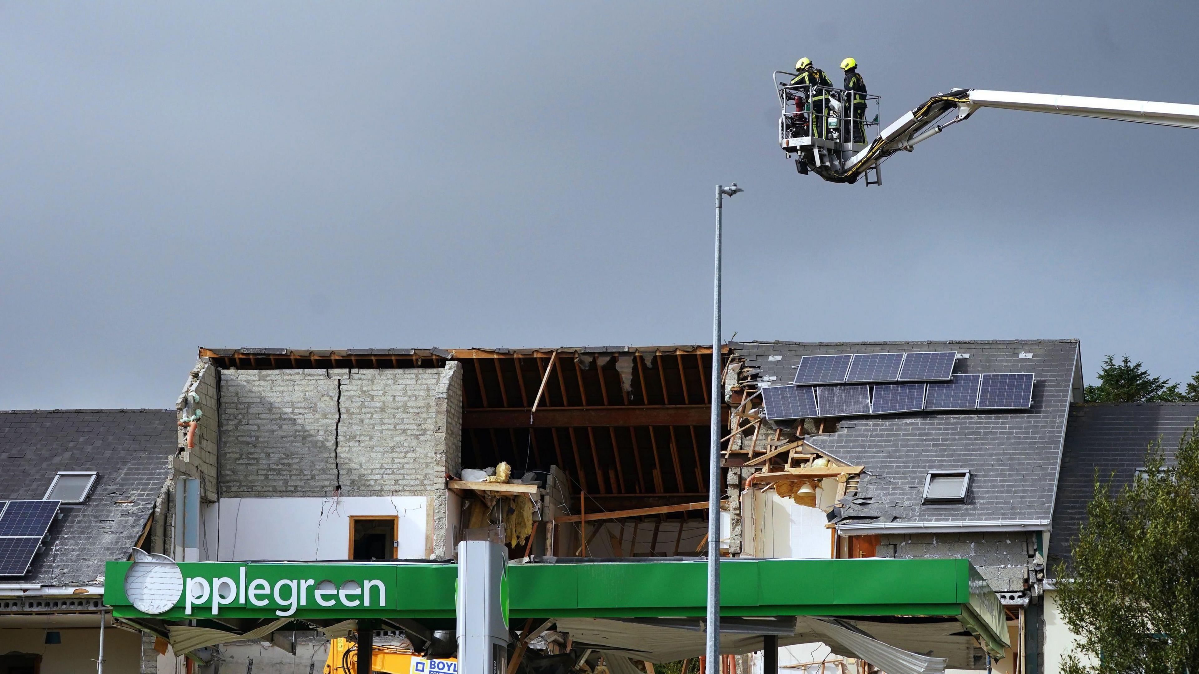 The building where the explosion took place, three quarters of the roof has been destroyed. At the front of the building, which would have been the roof over the fuel pumps, remains of the green 'Applegreen' sign are present.