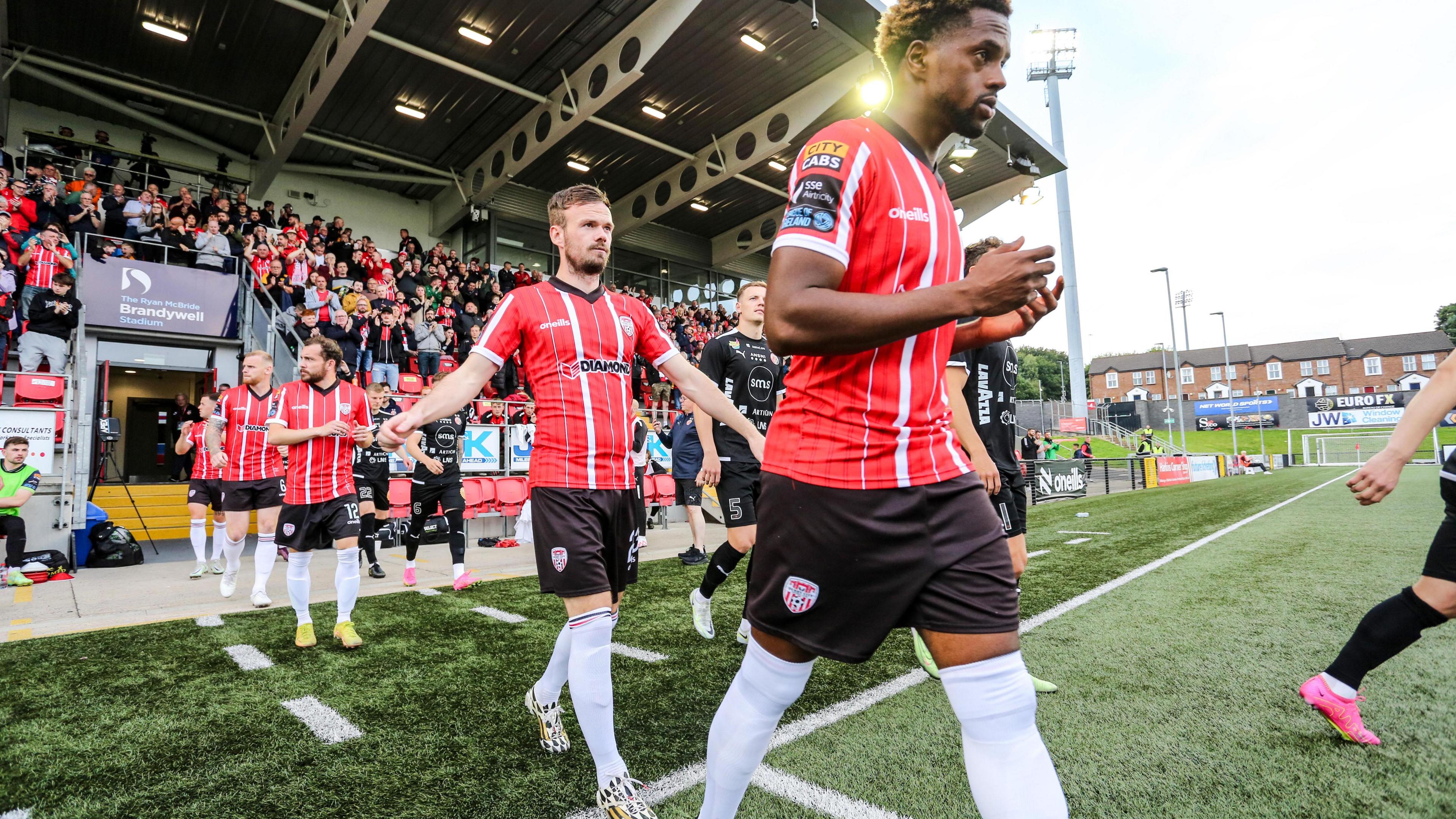 Derry City players walk out to the artificial Brandywell surface