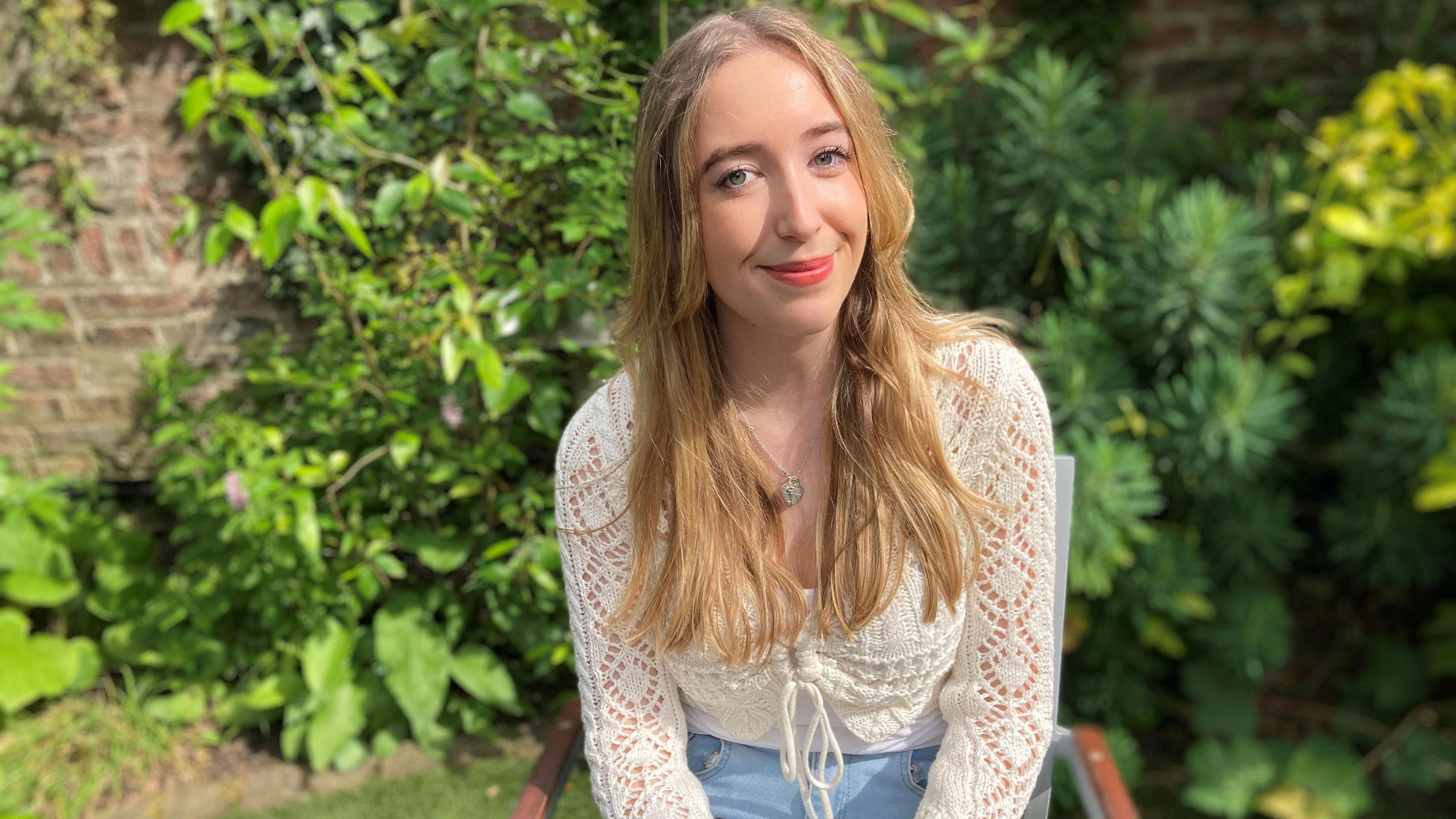 Lucie, in a white top, smiling at the camera