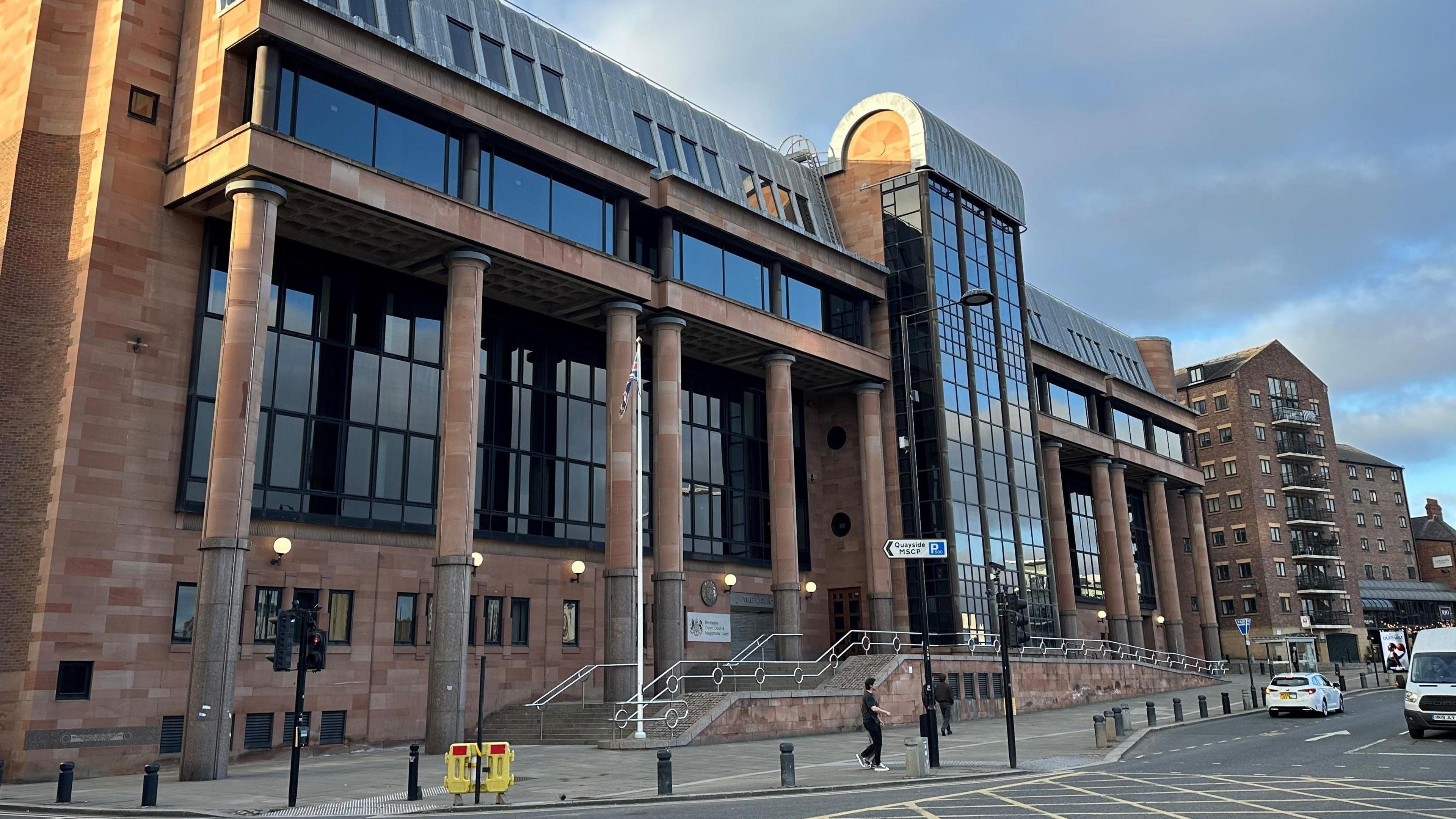 Newcastle Crown Court. It is a large imposing building made from red stones with columns and large dark windows