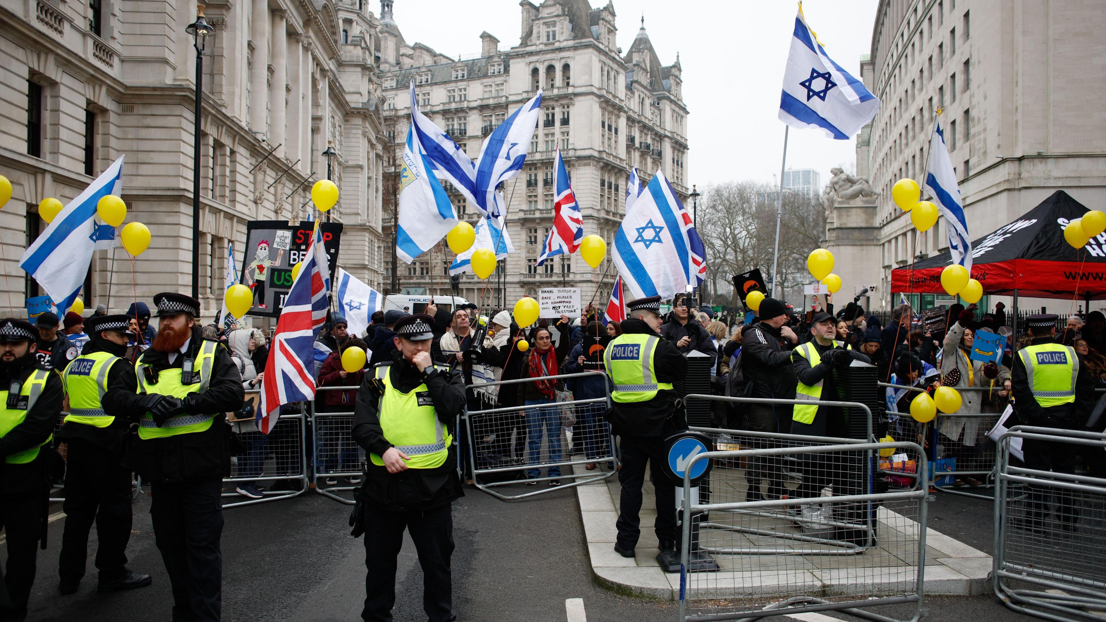 Police at a counter-protest rally, with demonstrators waving the flag of Israel