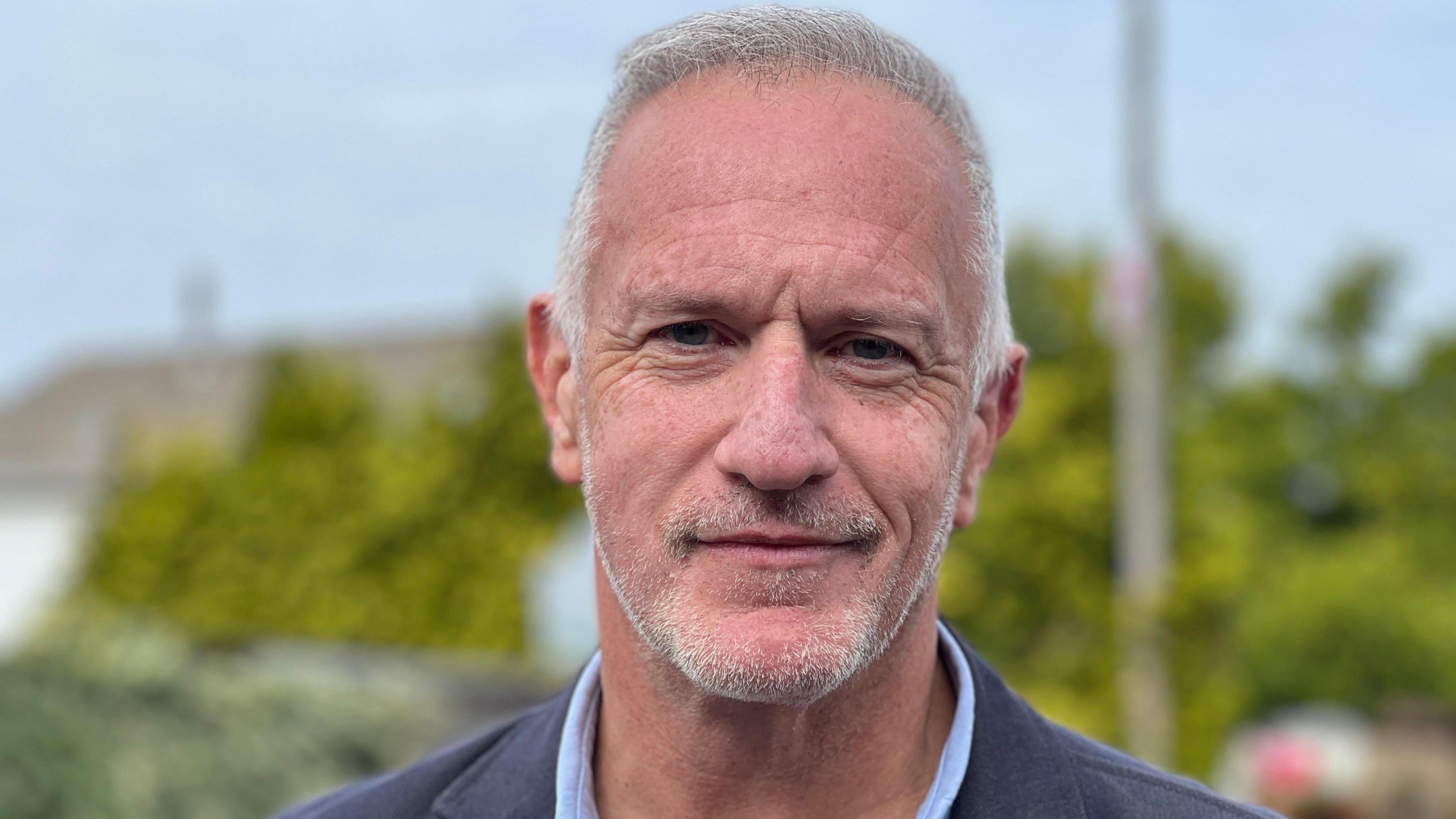 Councillor Ian Boulton. He has grey hair and a trimmed grey beard, and is wearing a blue jacket and a light blue shirt
