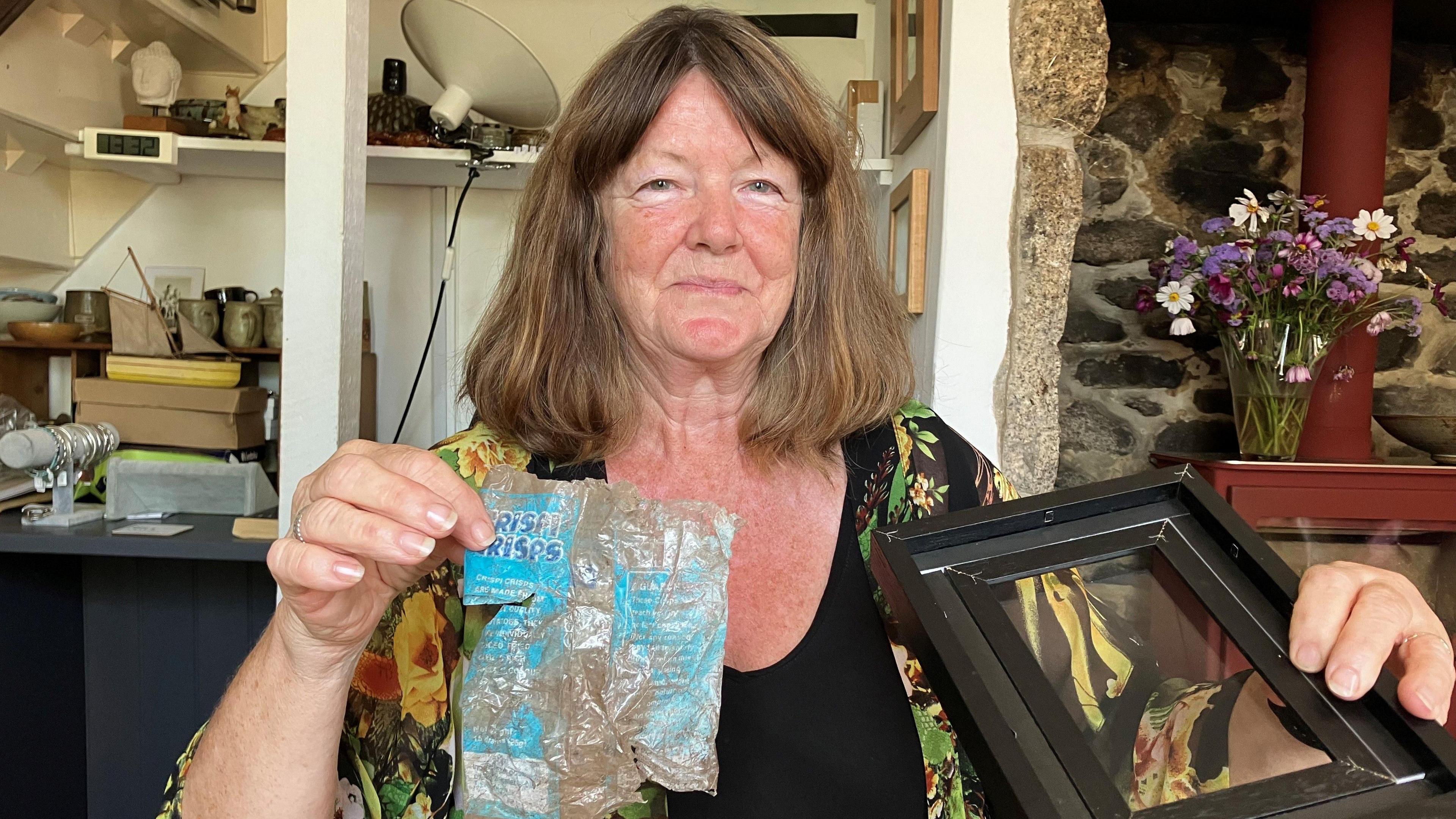 Woman holding crisp packet and picture frame