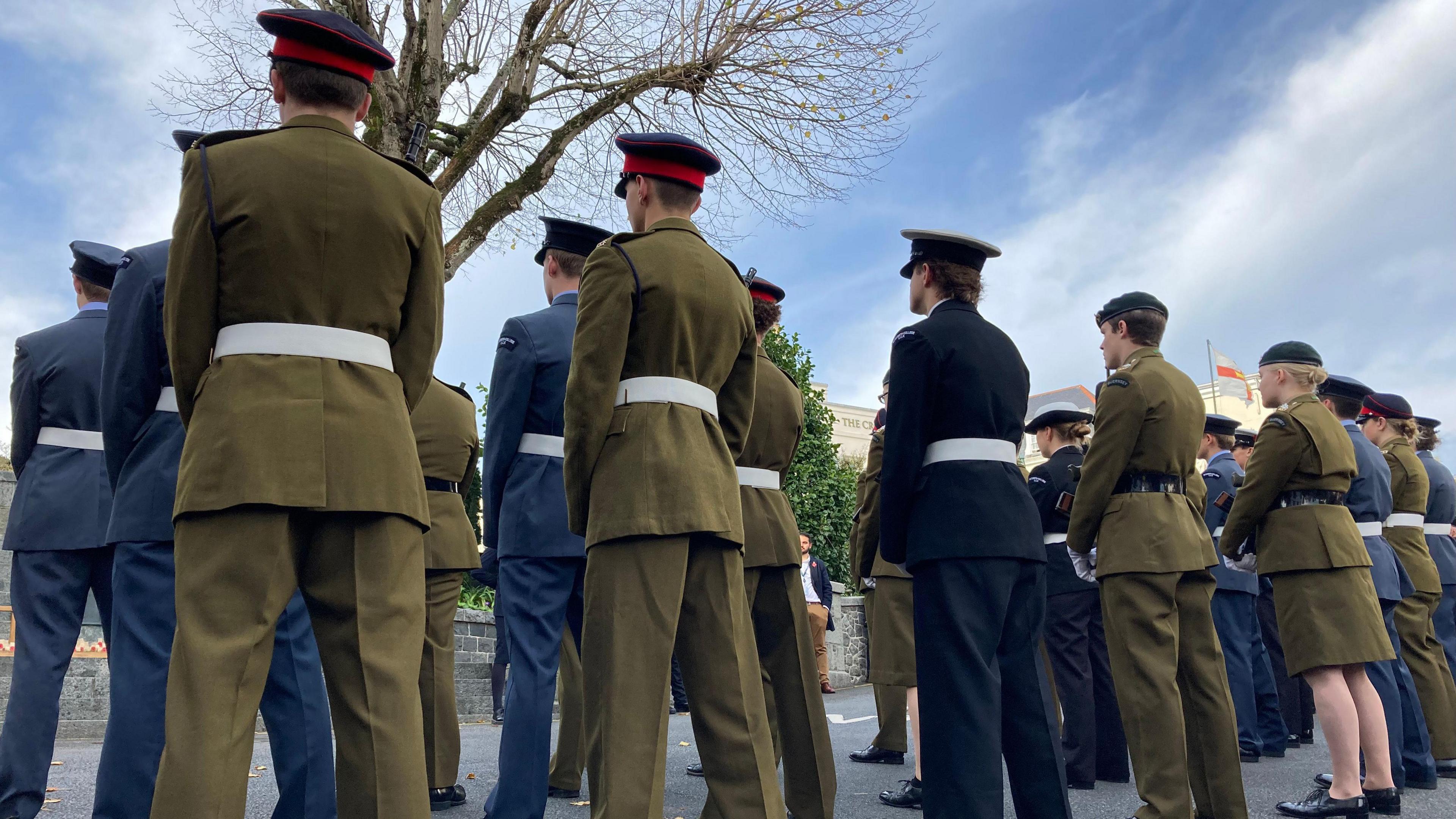 Image shows a row of military personnel dressed in olive green and navy blue suits, with matching berets/ caps, during the Remembrance Sunday service in St Peter Port, amidst a blue sky.