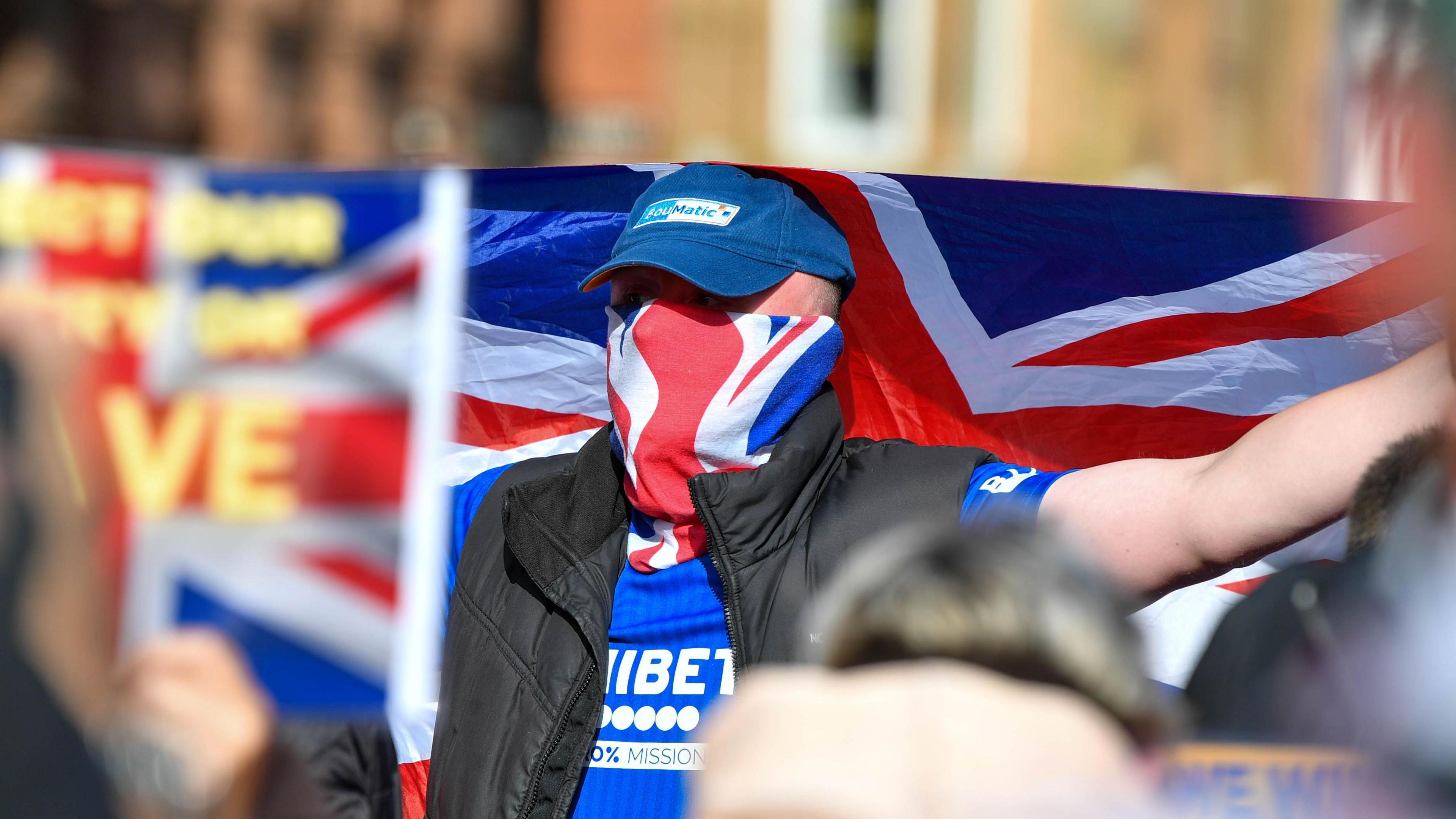 Man wearing blue Rangers shirt and union flag face covering