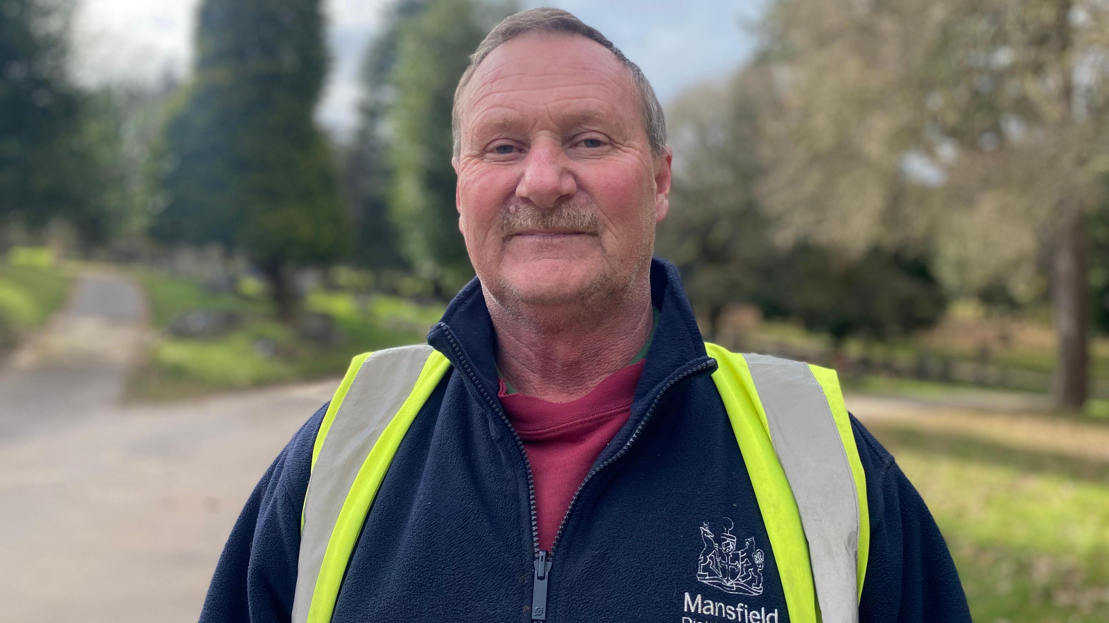 Picture of a man in a hi-vis in a graveyard