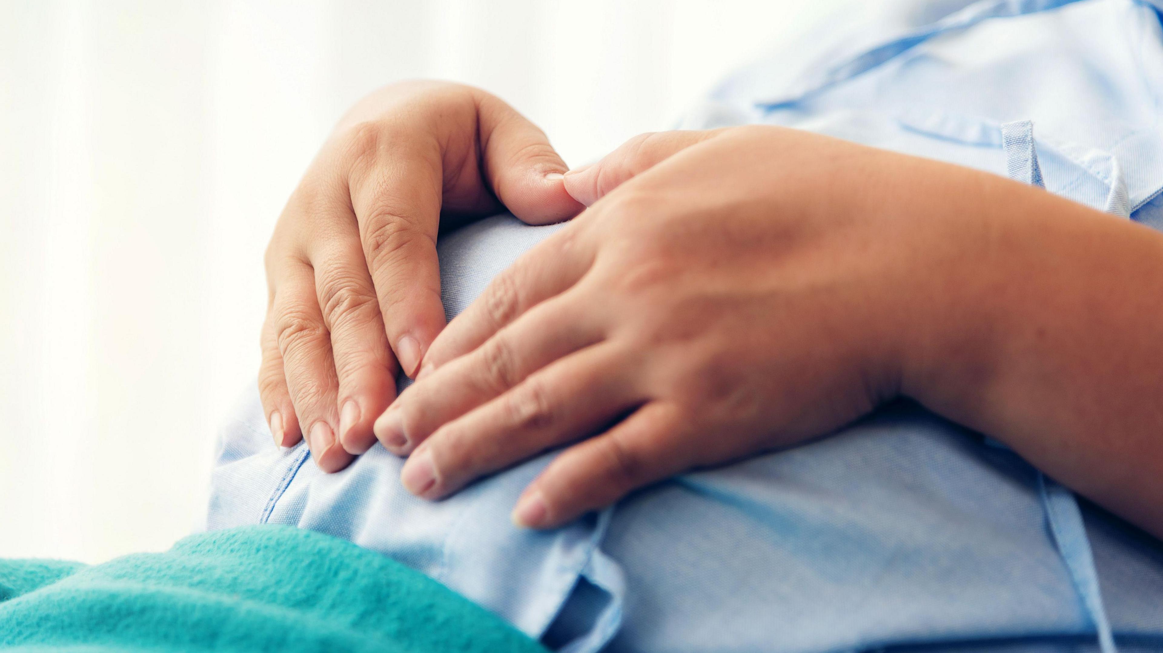 The tummy of a pregnant woman lying on the bed waiting to give birth in a hospital.