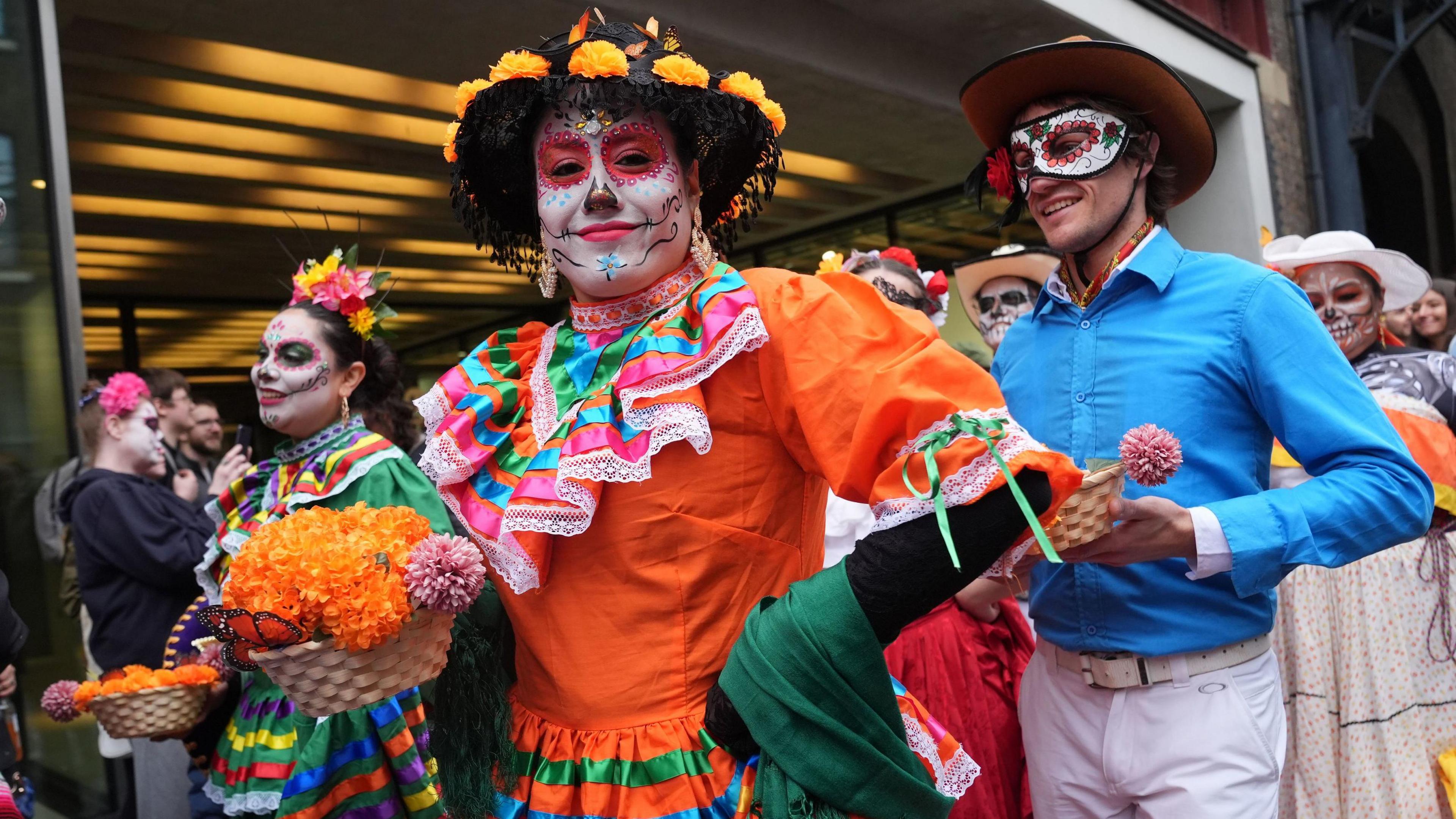 A woman dressed as La Catrina holds a basket of marigold flowers, during festivities in London.