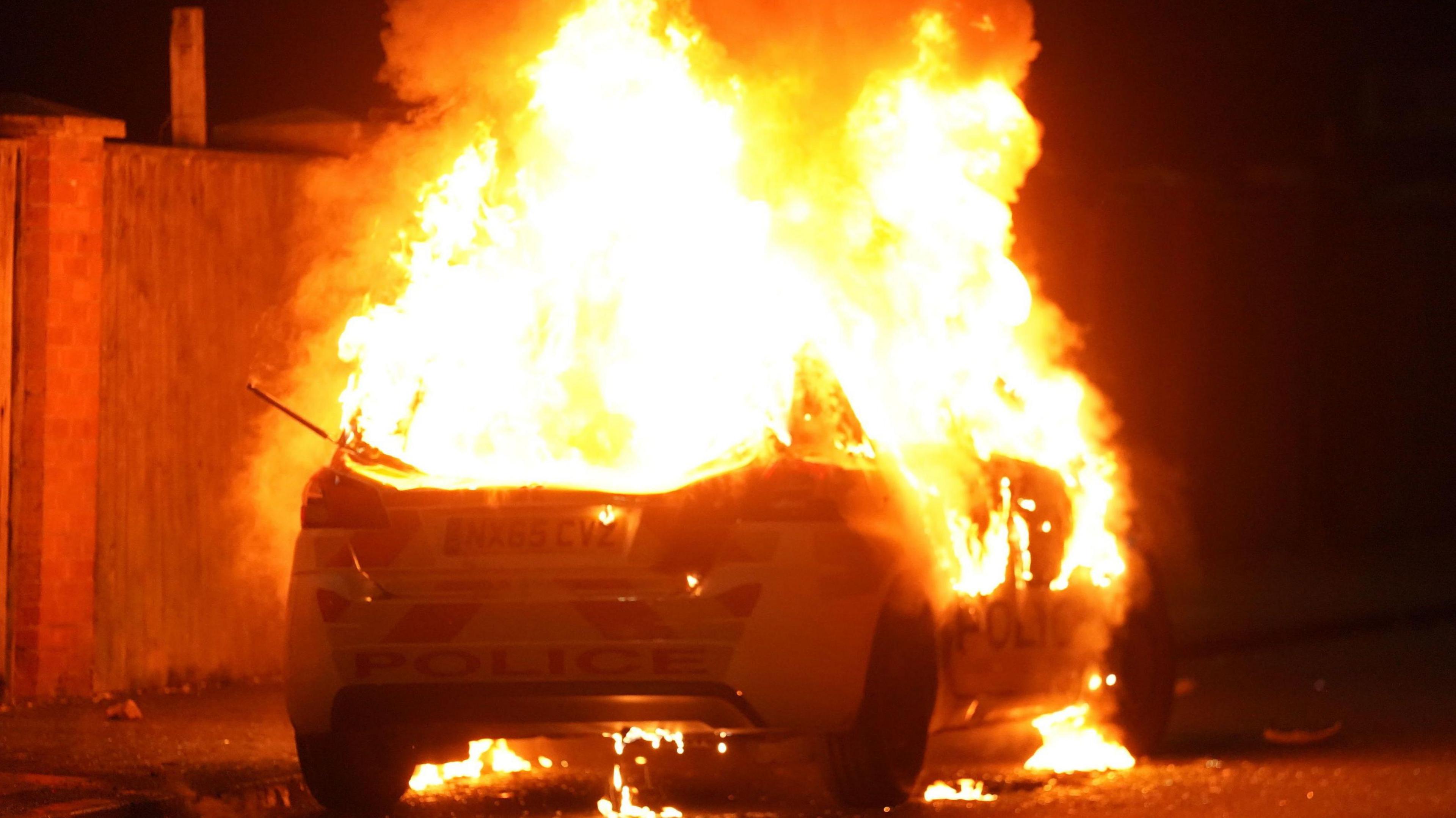 Police car set ablaze in disorder following fake online news about the identity of the alleged murderer of three little girls in Southport