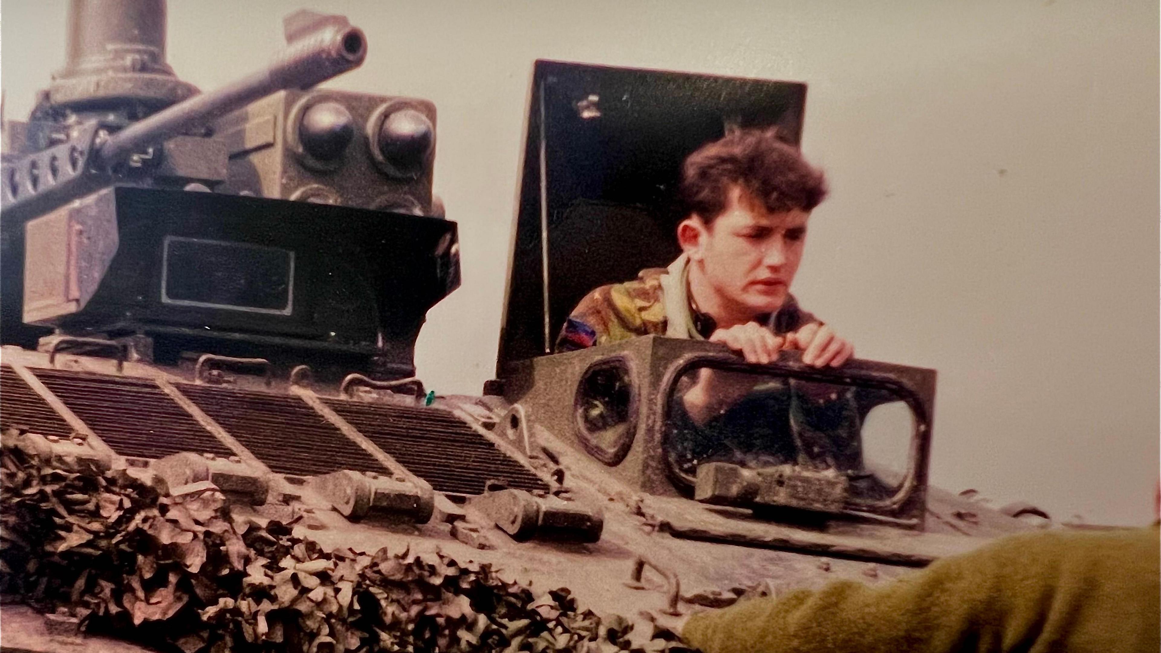 Darren Horvath popping his head out of the top of a military vehicle