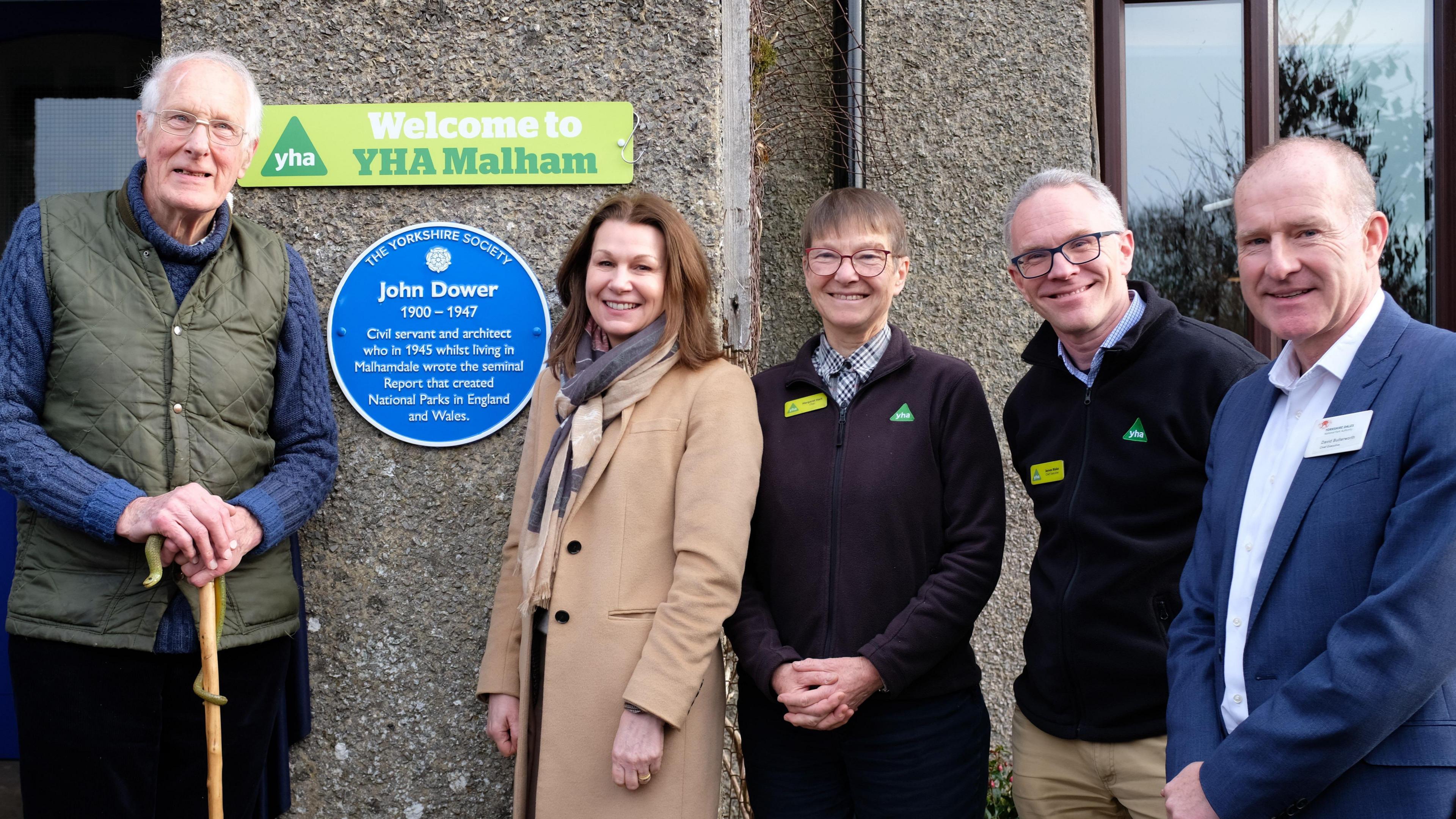 Robin Dower, Baroness Hayman, Margaret Hart, James Blake and David Butterworth stood next to the blue plaque at Malham Youth Hostel.