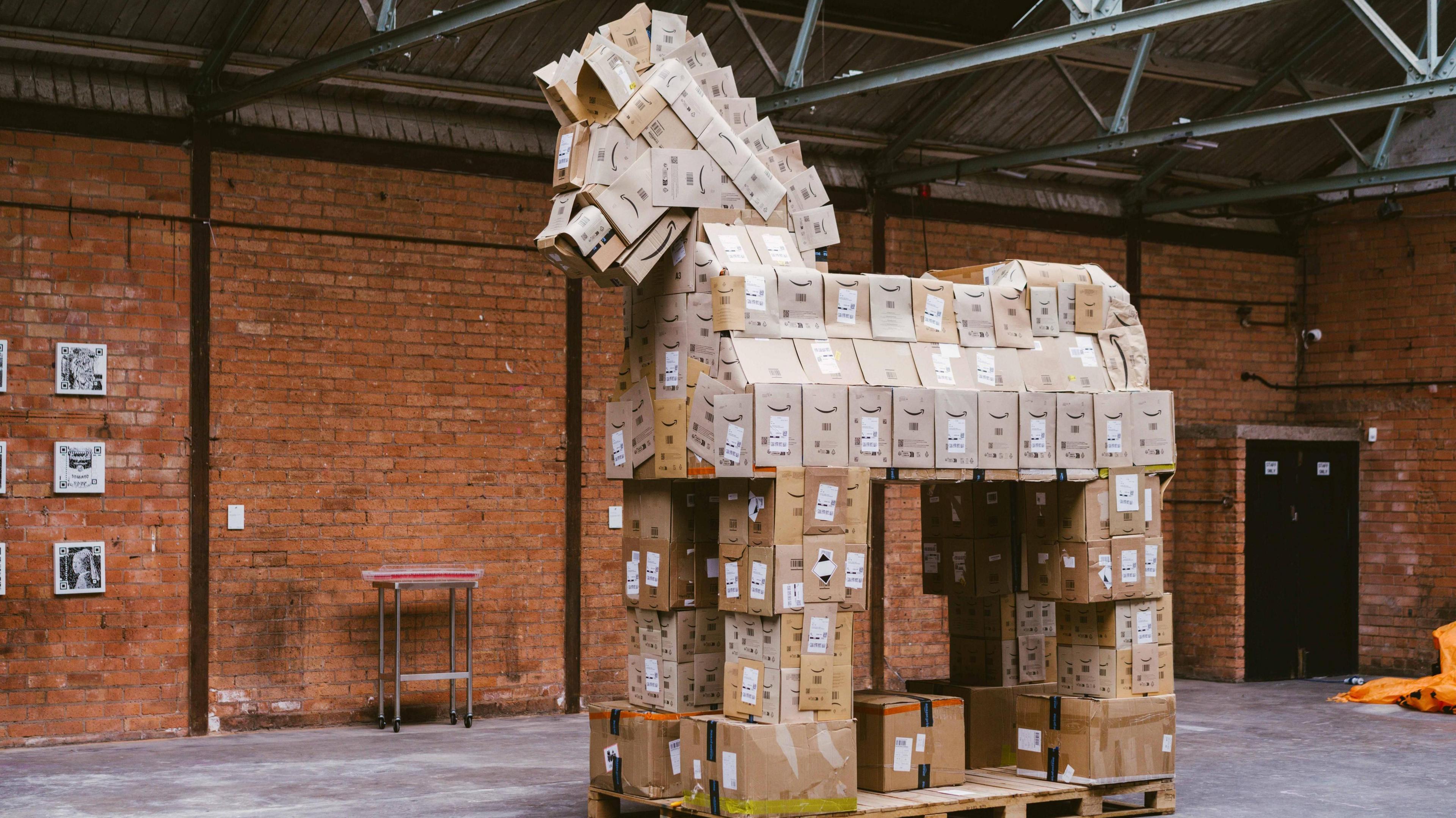 A trojan horse sculpture is built from cardboard boxes and standing in a warehouse