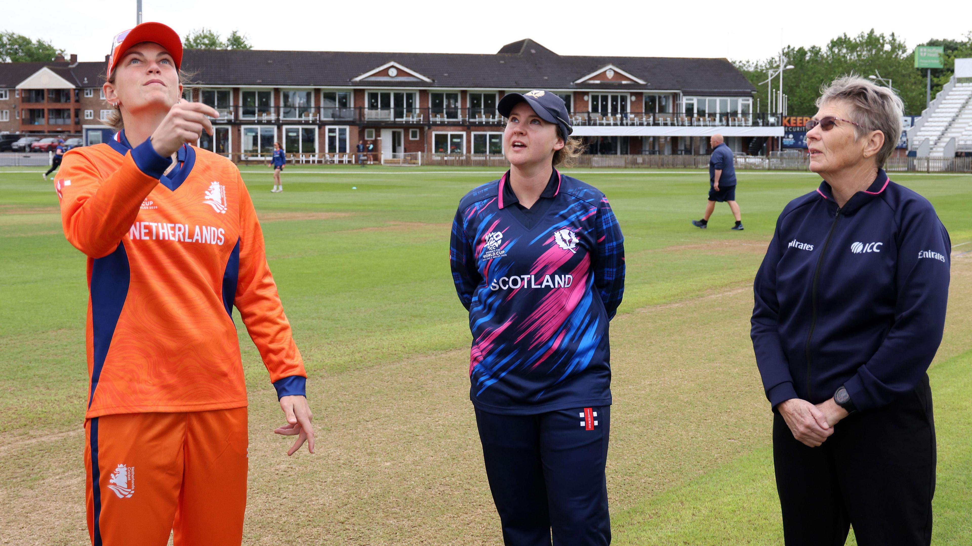 Netherlands captain Babette de Leede tosses up, watched by Scotland captain Kathryn Bryce and an umpire