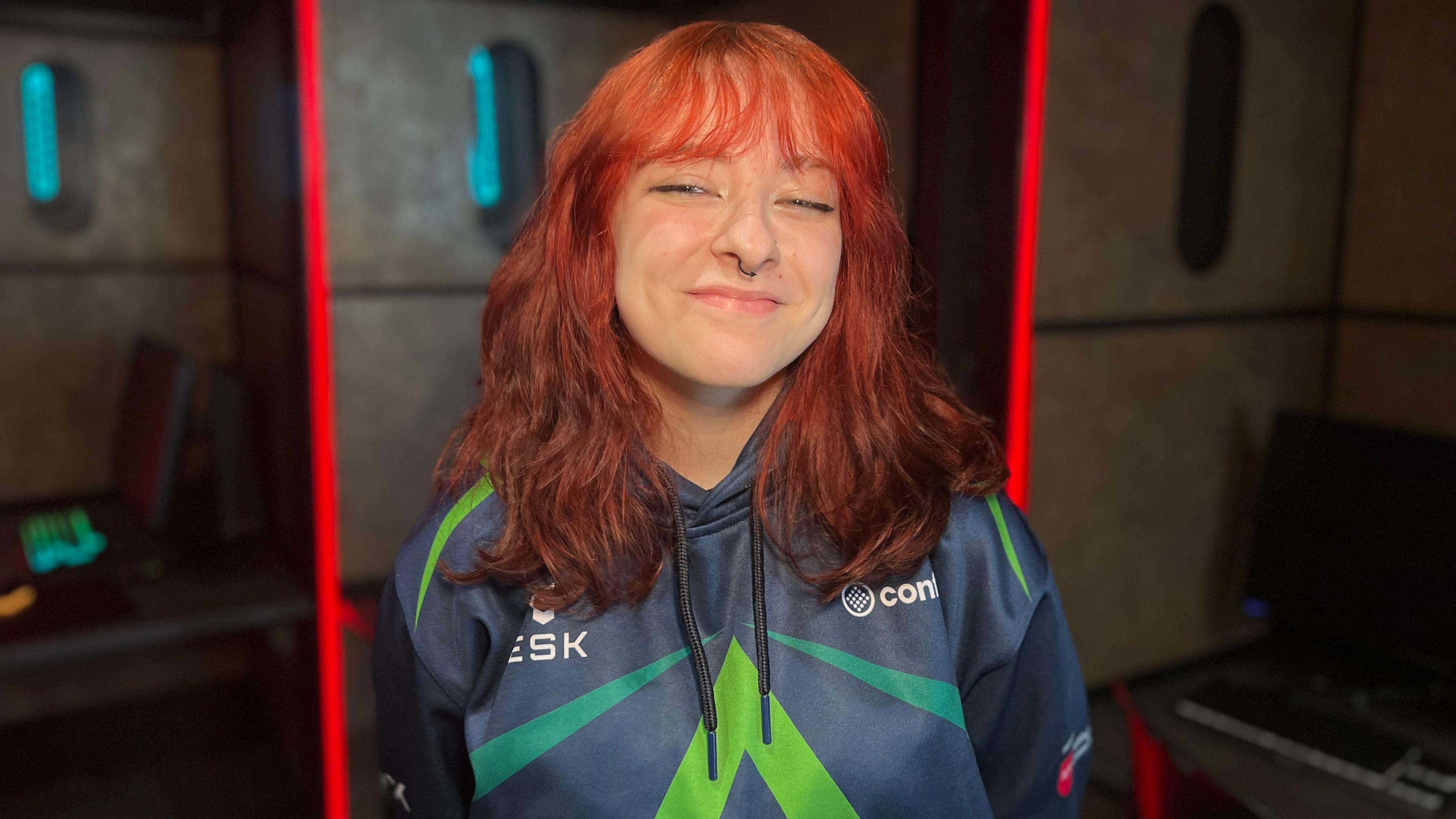 Arkay smiling at the camera wearing a blue and green Confetti Arrows hoodie