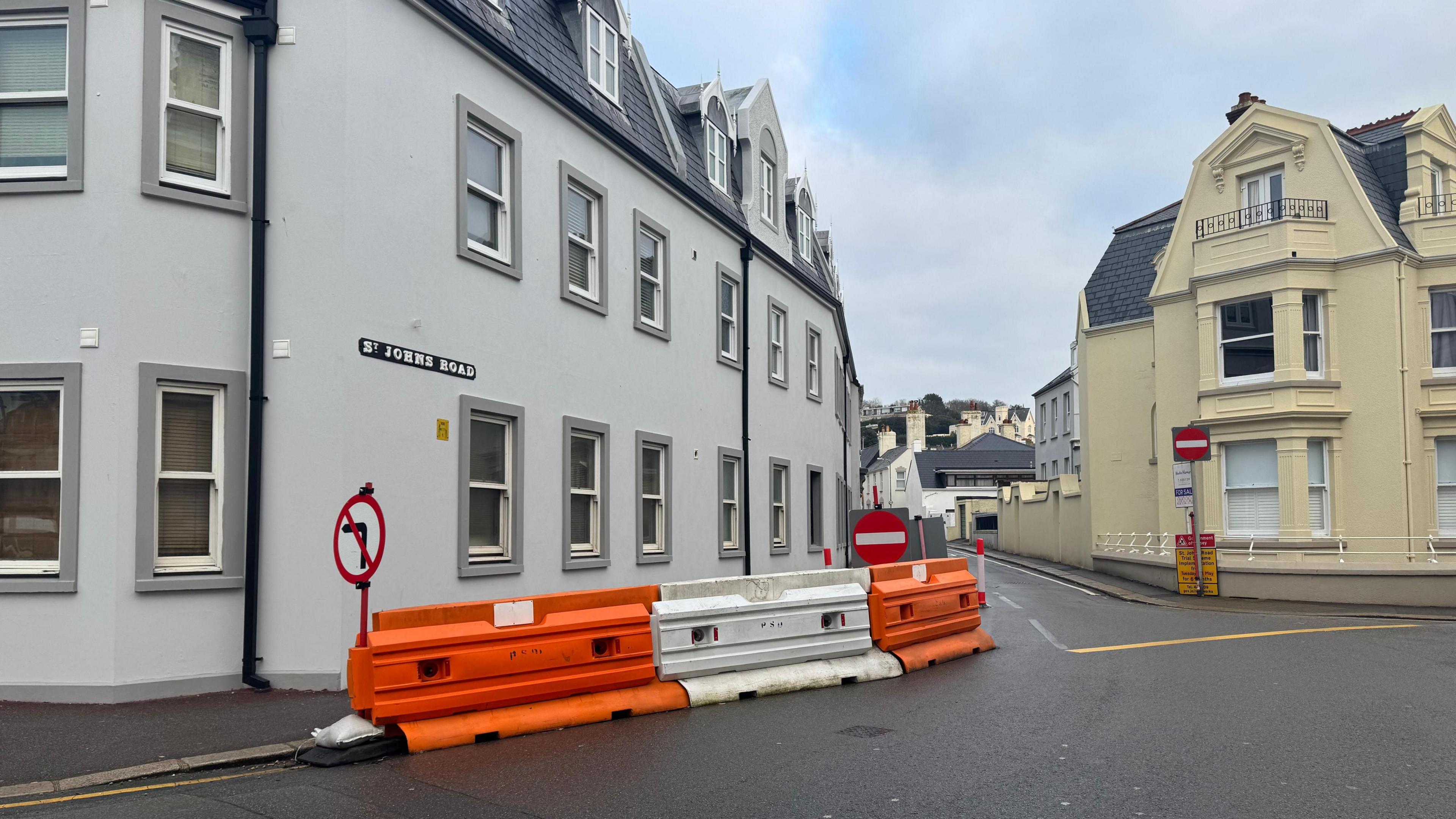 St John's Road in St Helier with road signs blocking one side of the road surrounded by two storey buildings.