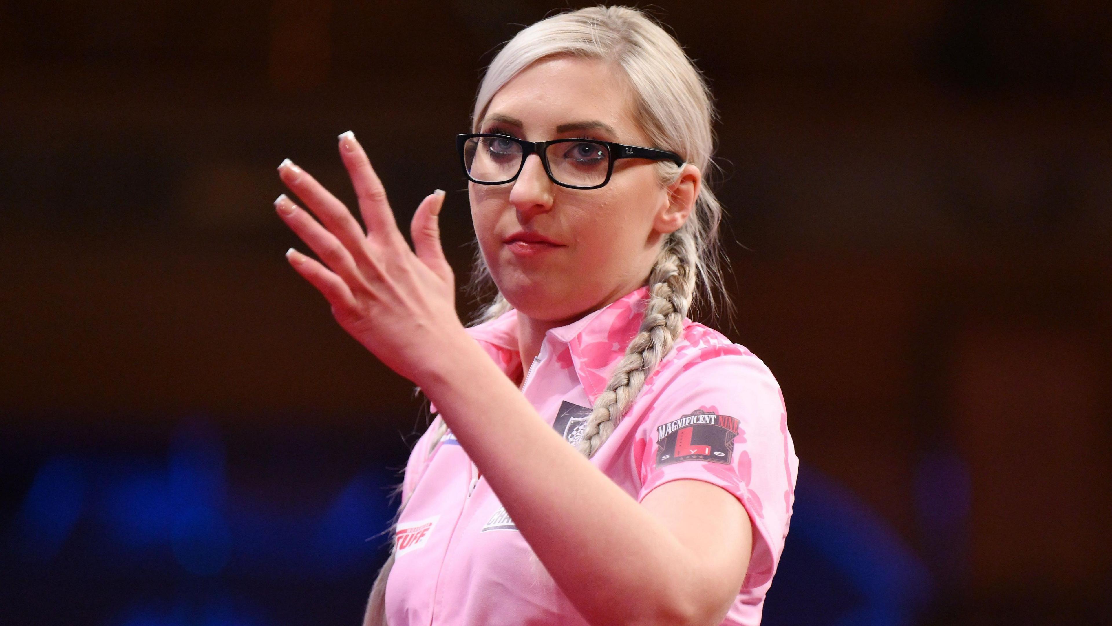 Fallon Sherrock waves her hand during a darts match