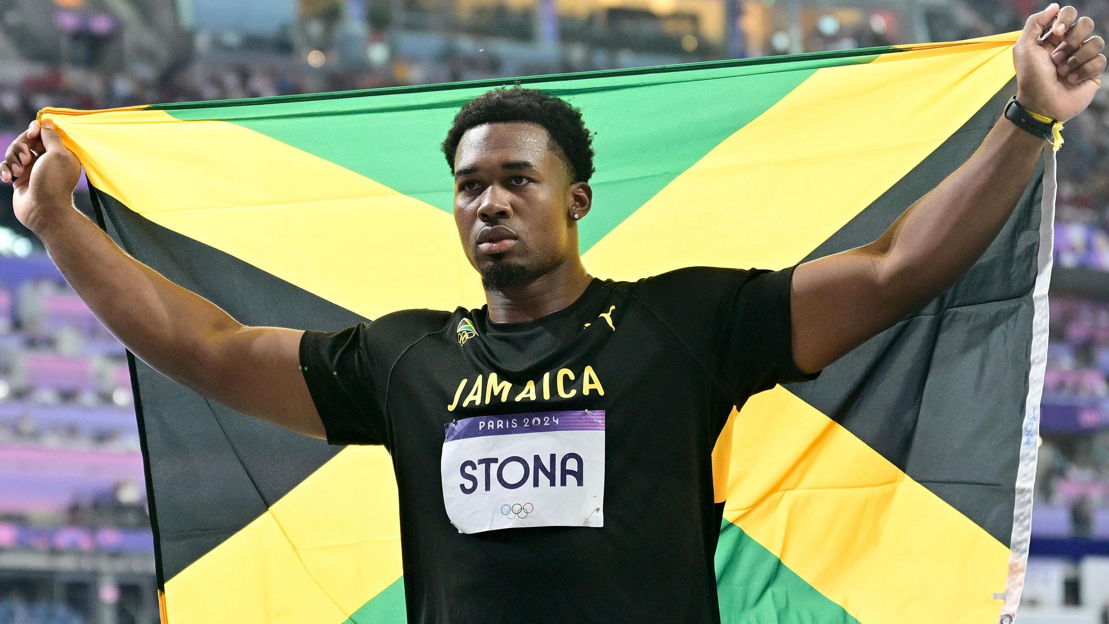 Roje Stona poses with the Jamaica flag after winning Olympic discus gold in 2024