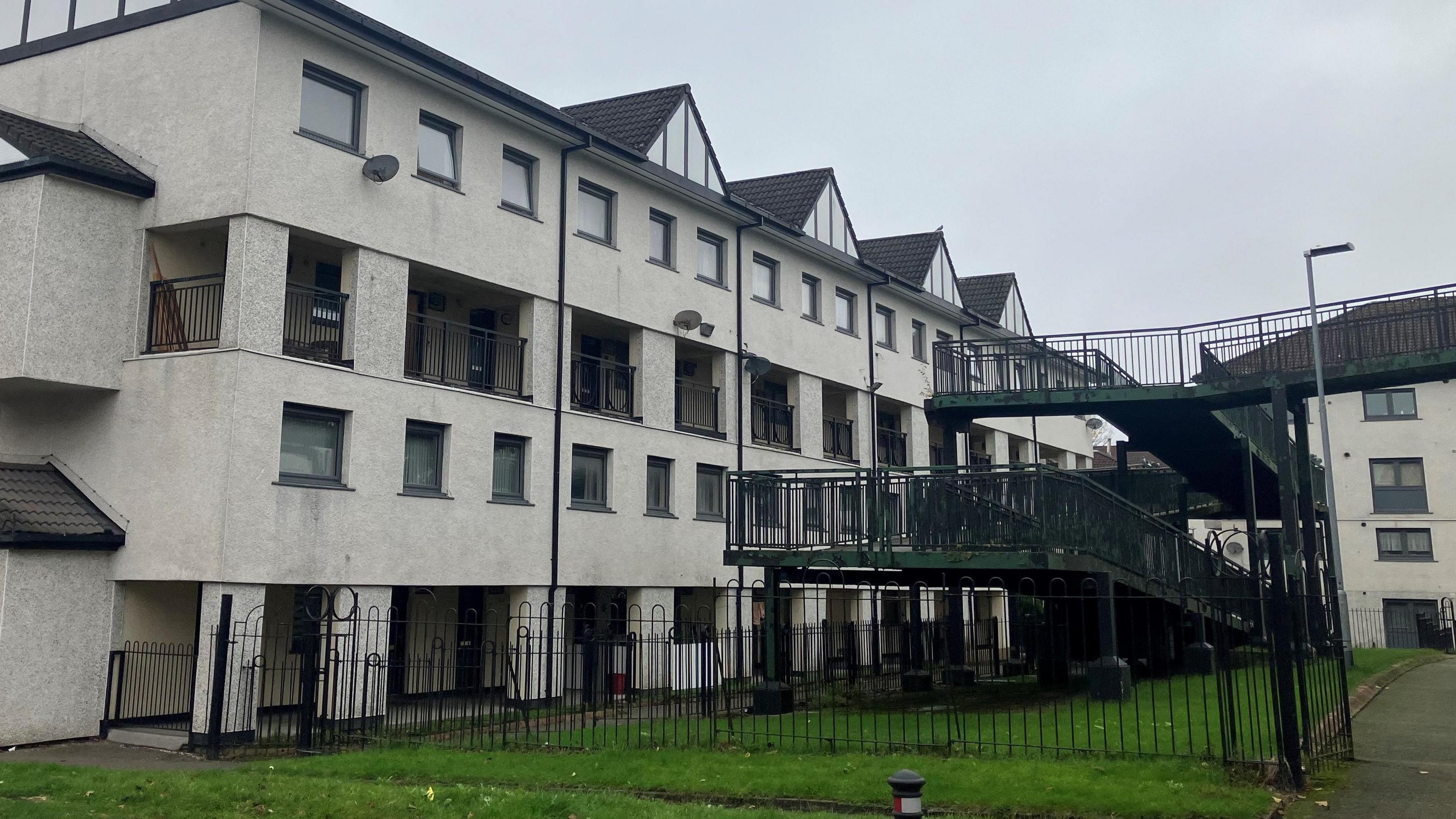 Four-storey blocks of flats on Rochdale's Freehold Estate. There are balconies, covered passageways and elevated walkways and bridges with black iron railings. The photograph was taken on a grey, cloudy November day.