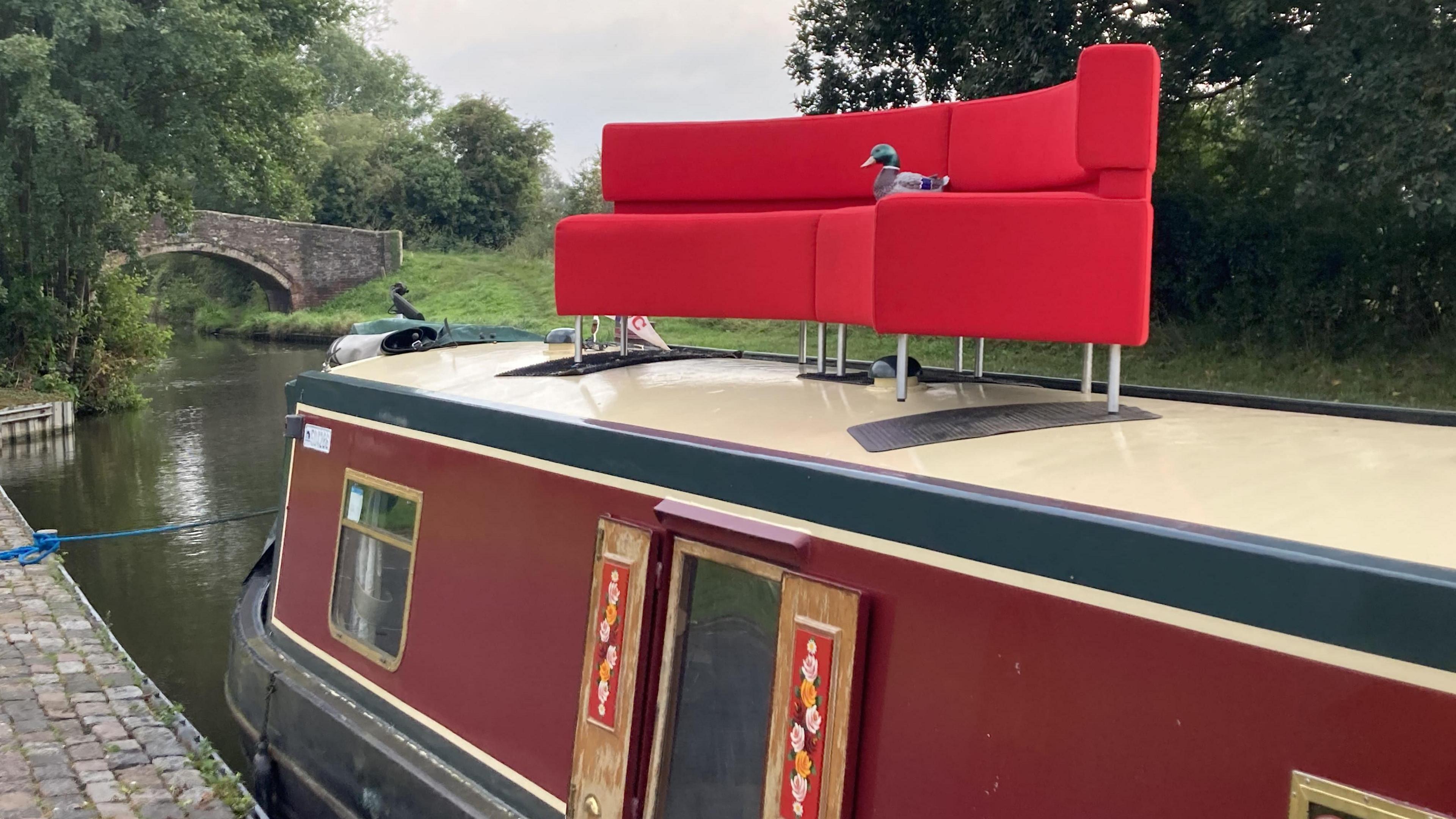 The red sofa on a canal boat at Stafford Boat Club, with a ceramic duck on sitting on the sofa