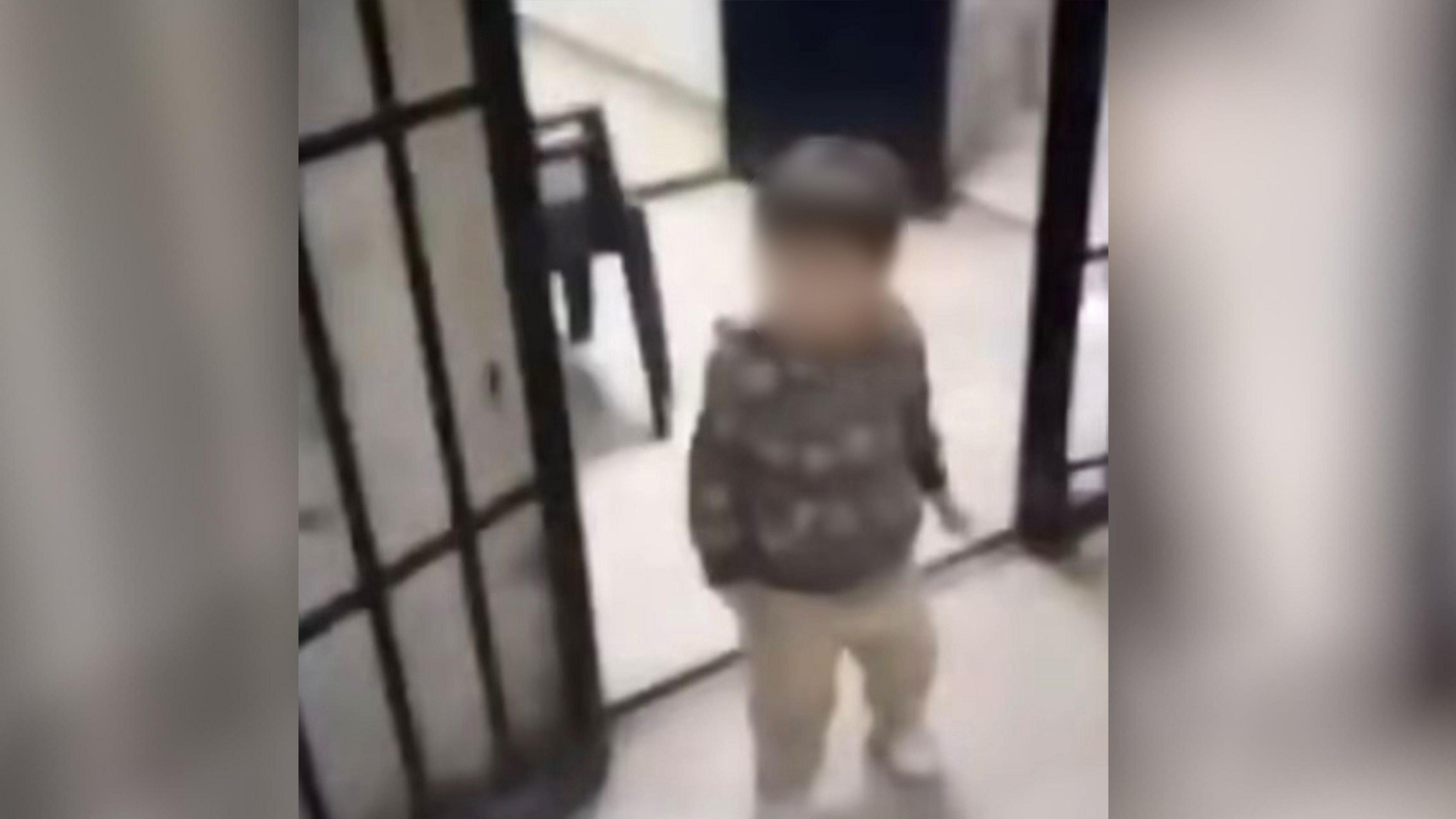 A toddler, no more than 3 or 4 years of age, walks through an open cell door.