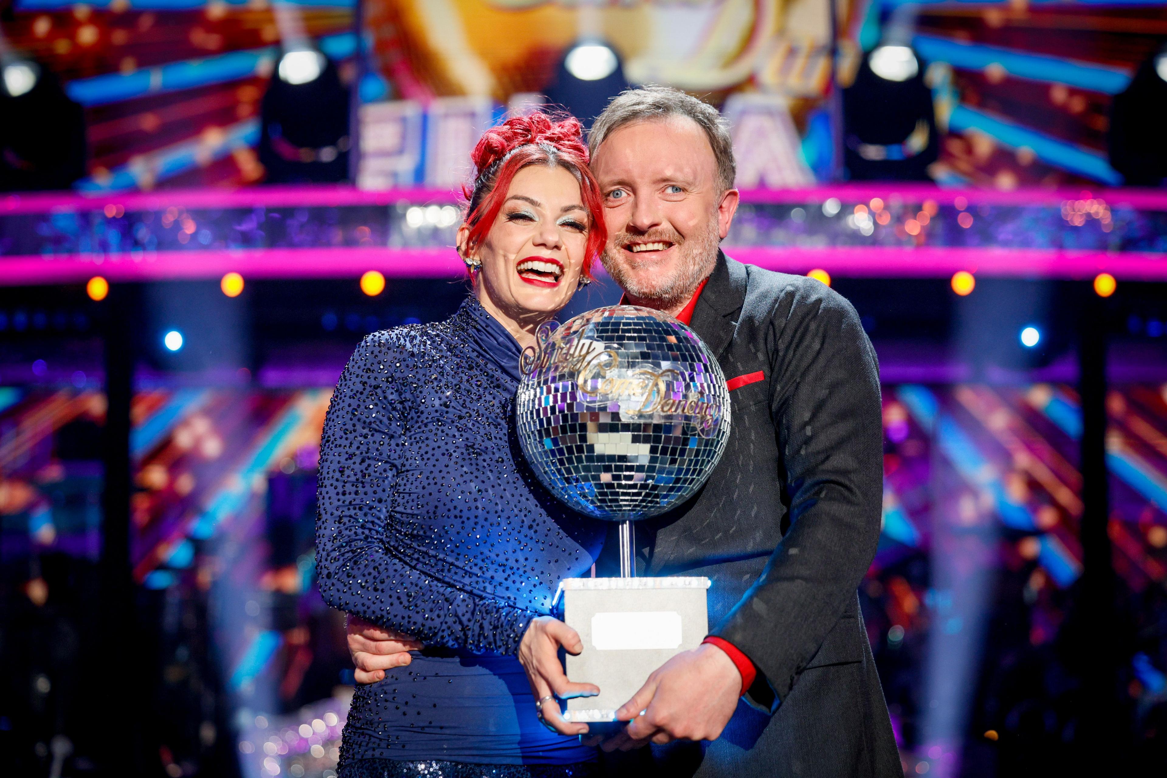 Dianne Buswell and Chris McCausland holding the Glitterball trophy