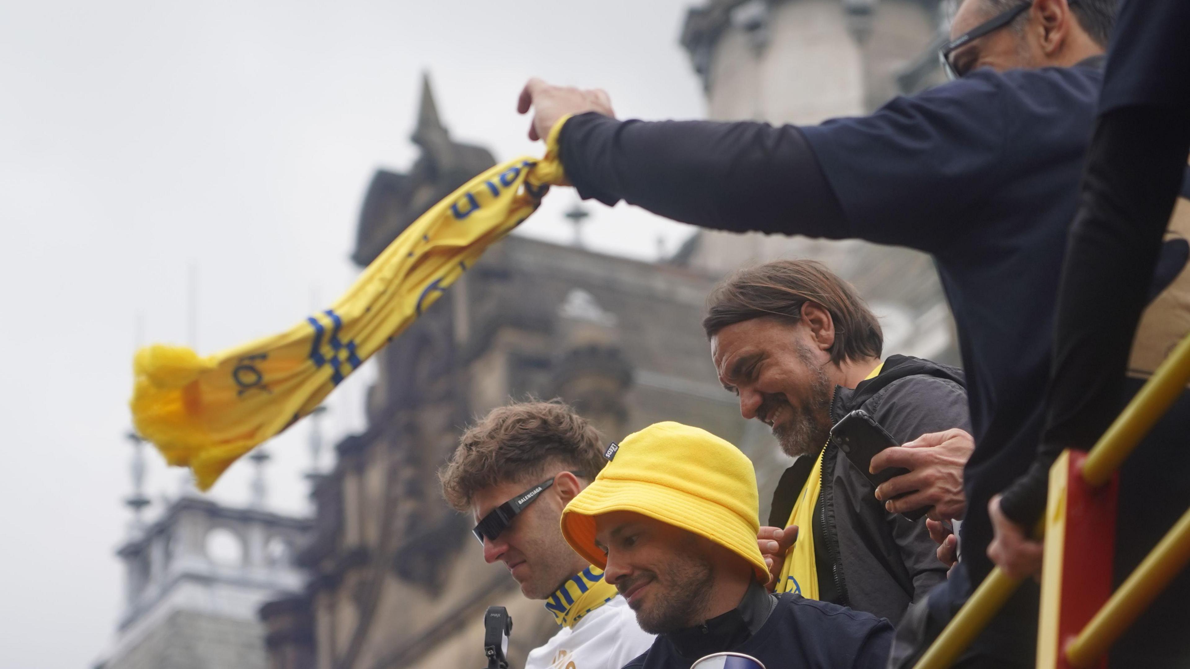 Man waves flag on top of bus 