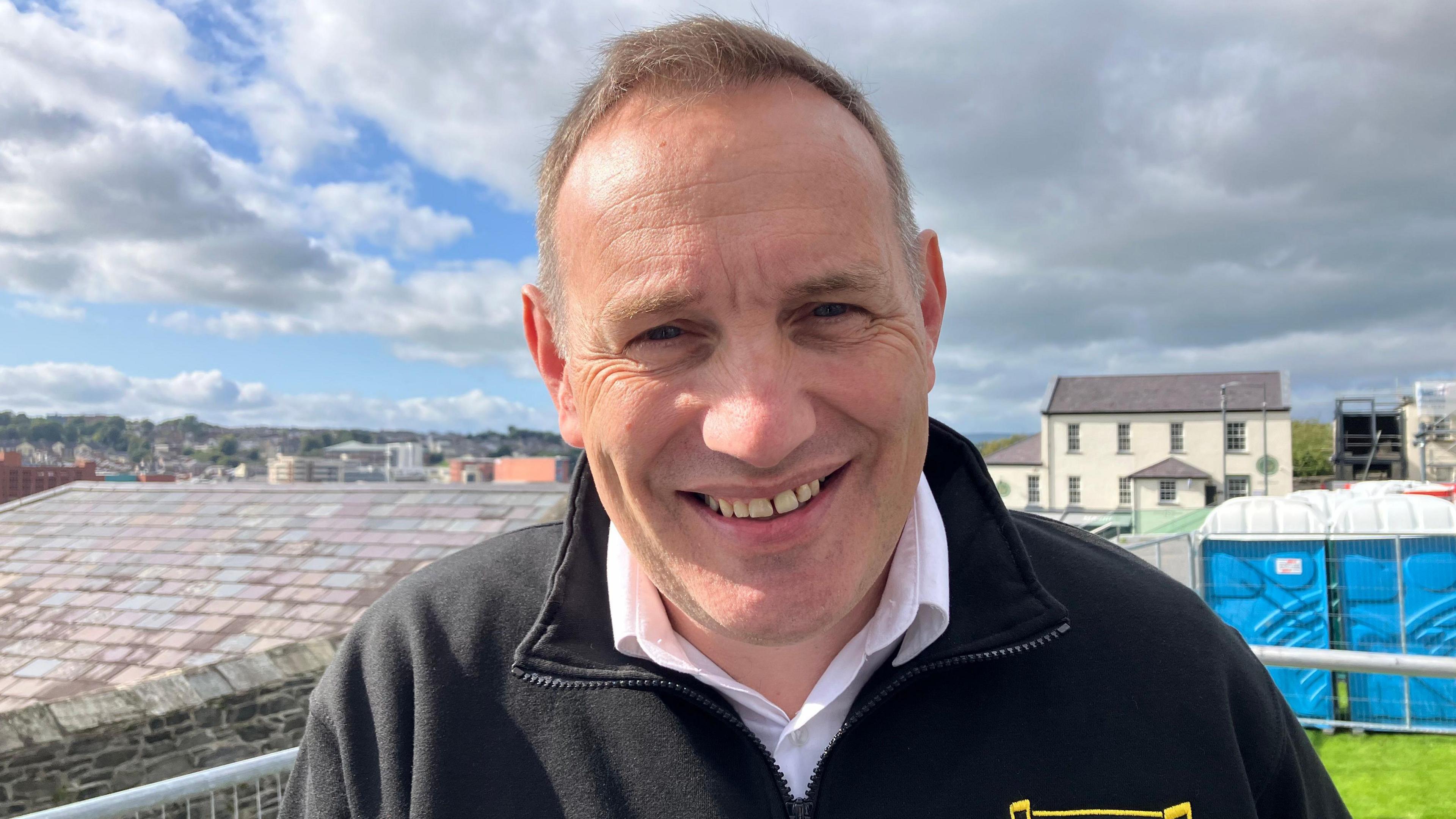 Karl Diamond. He has short brown hair, wearing a white shirt and black zip fleece.