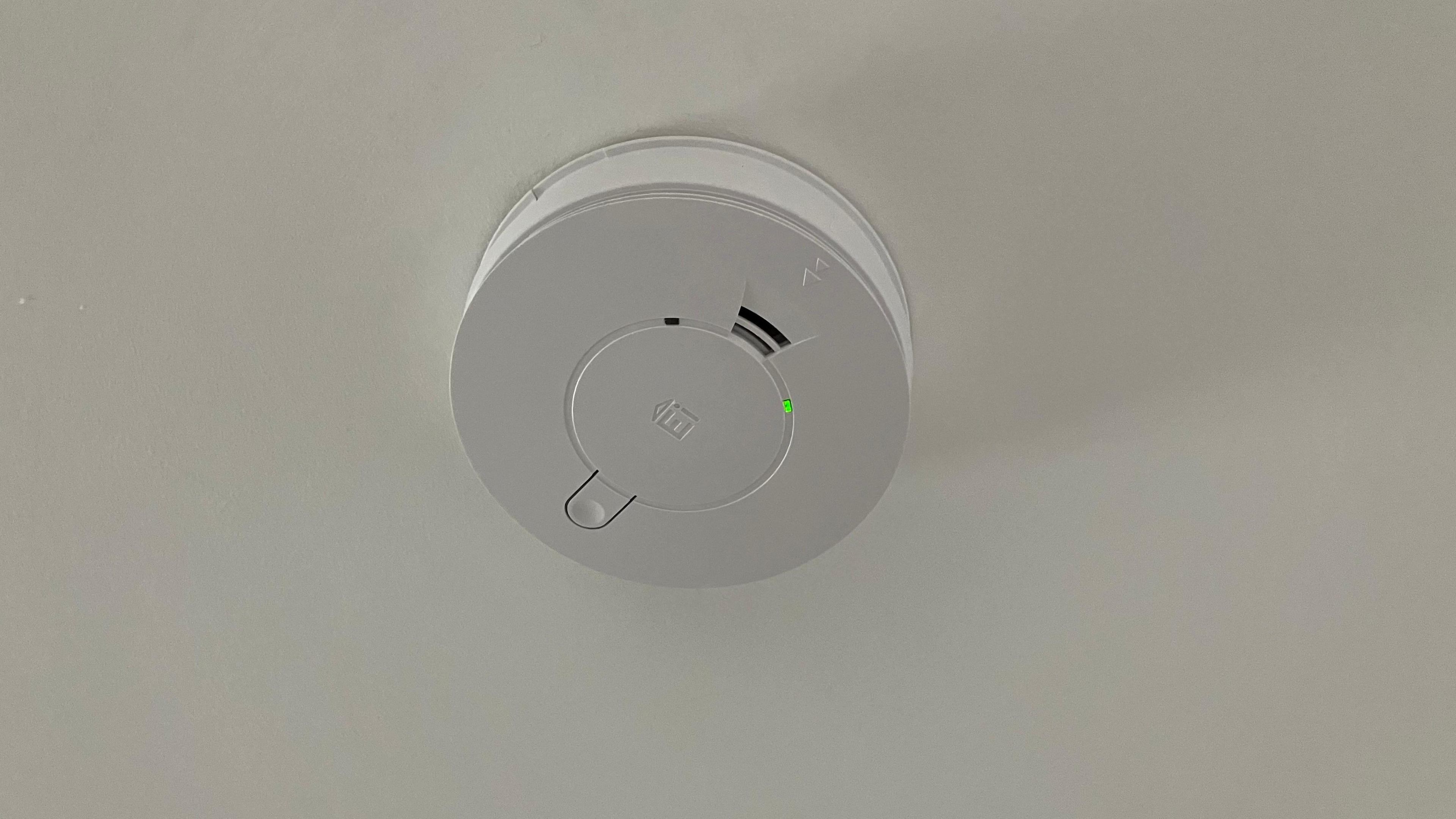 A white carbon monoxide alarm on a ceiling. 