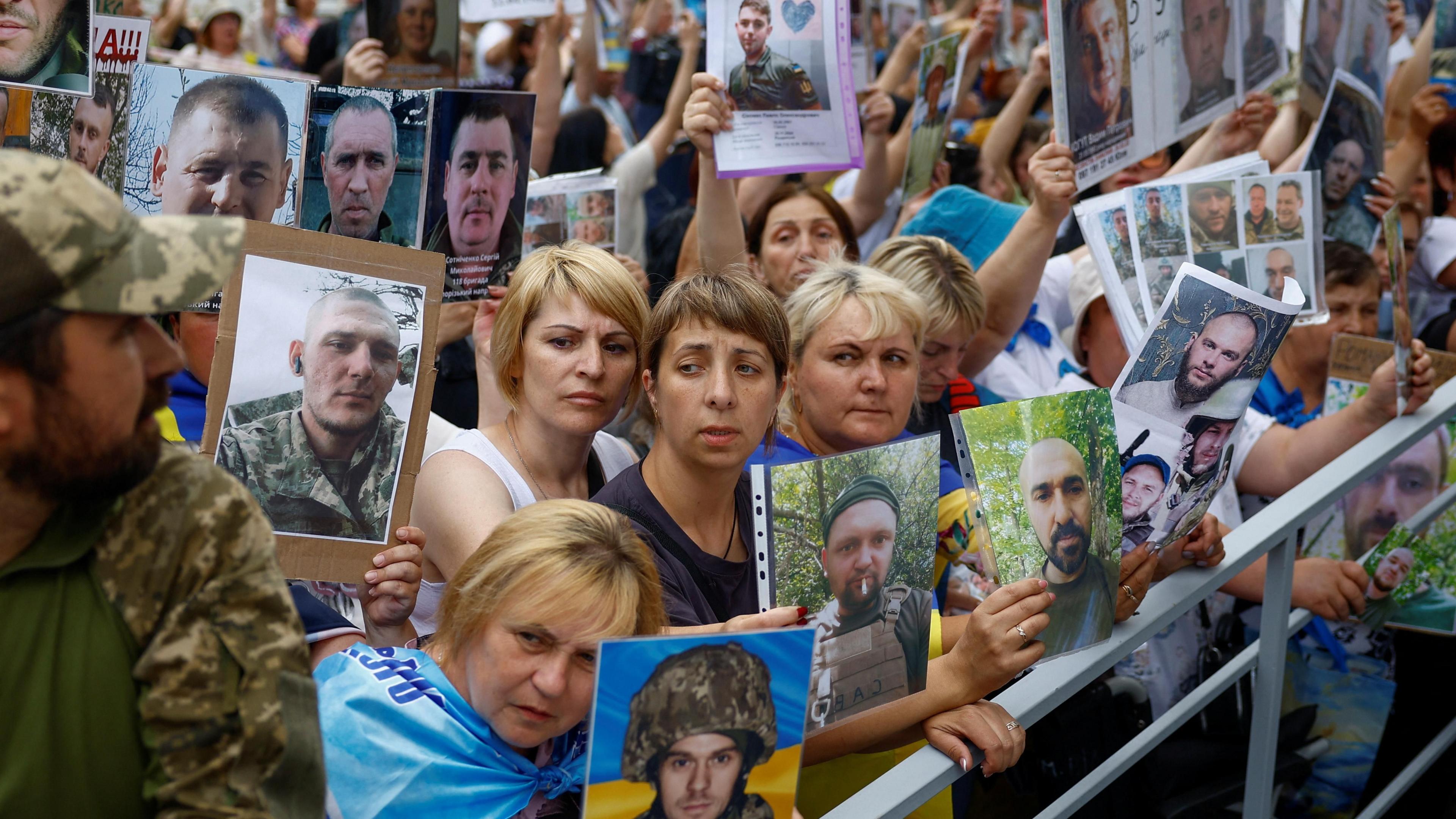 People hold portraits of their relatives, Ukrainian prisoners of war (PoWs) and missing soldiers, as a planned exchange takes place