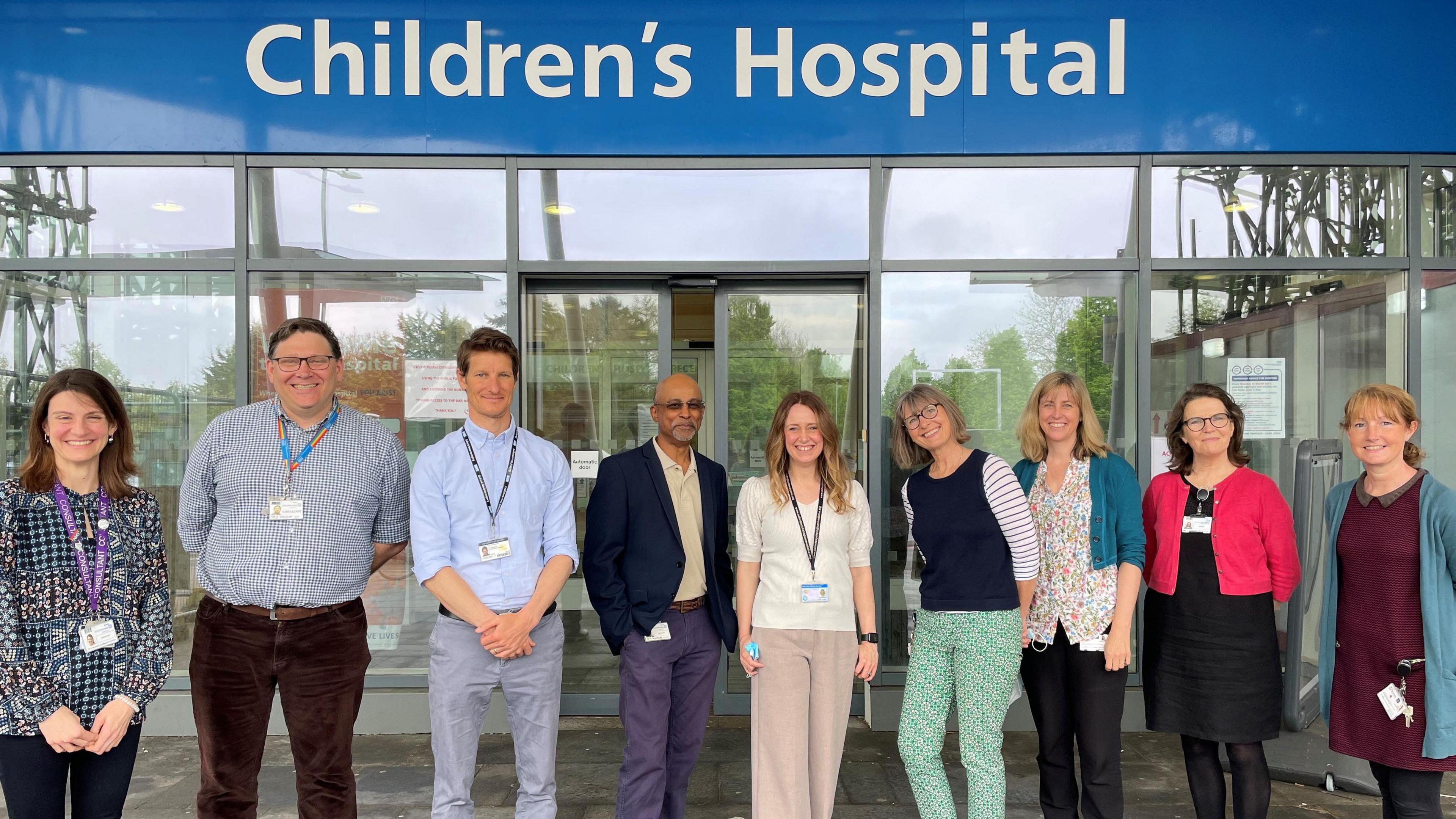 The Oxford Tom's Trust team smiling for the camera at the Children's Hospital entrance. There nine people in the group.