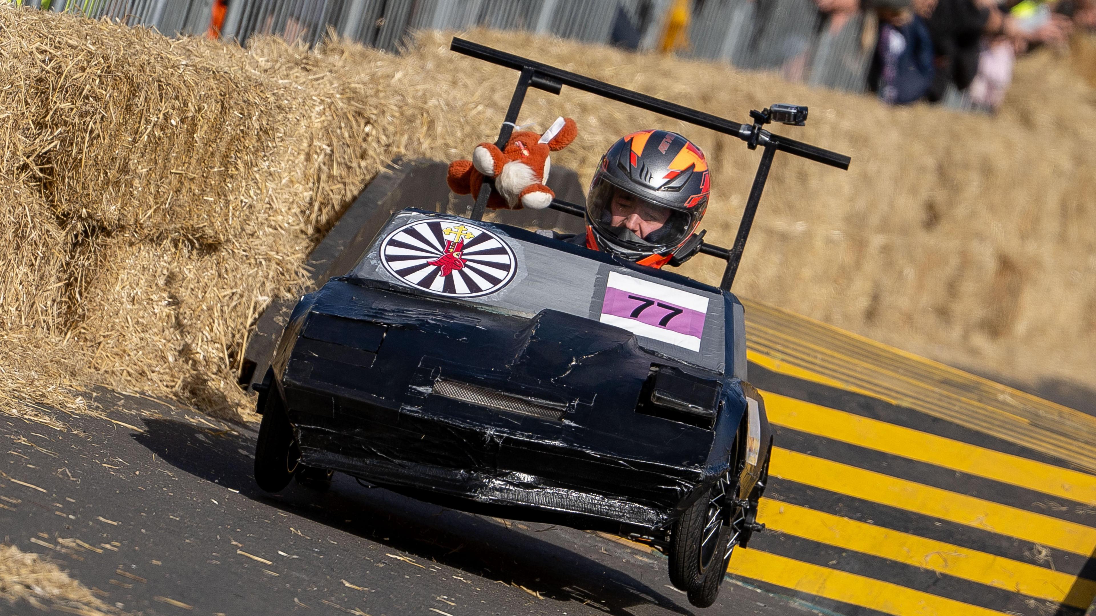 A grey kart where the front has been stuck together using black duct tape. A number 77 is taped onto the front of the kart alongside a bullseye. 