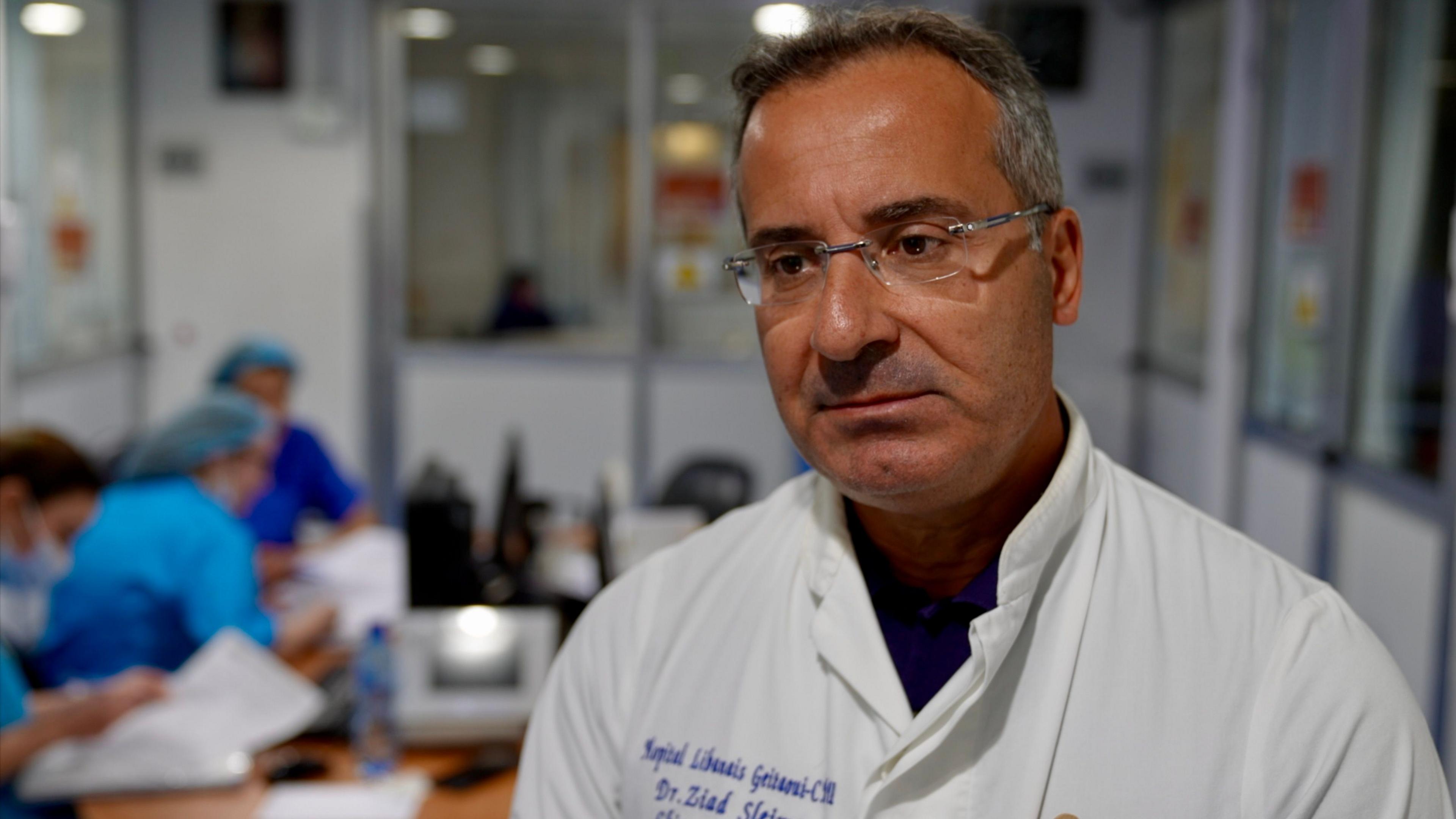 A man in a white coat and glasses