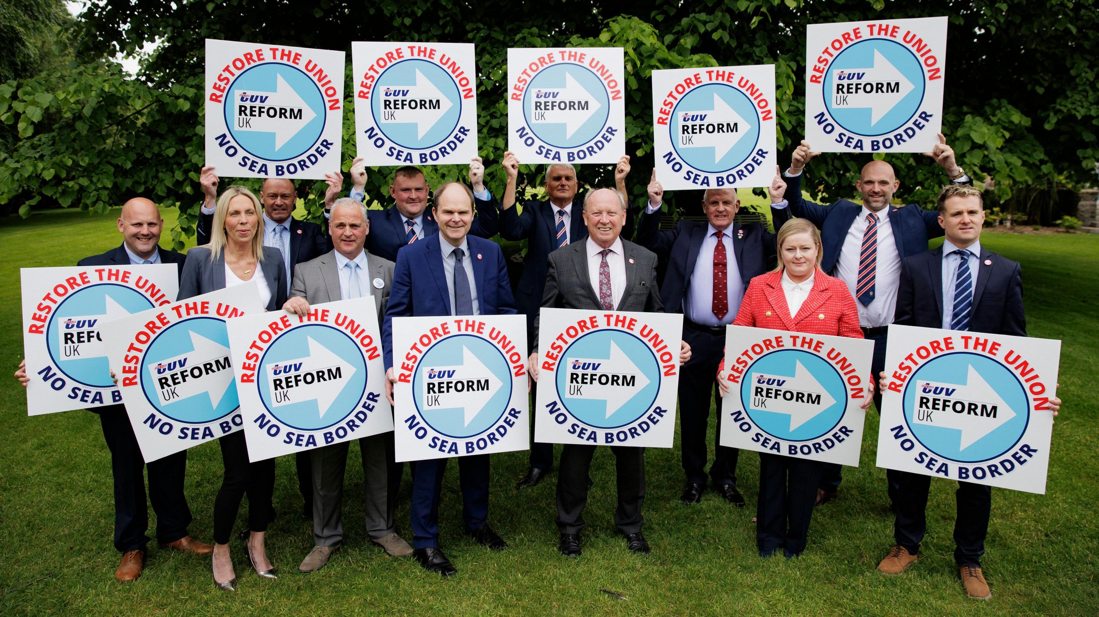 The TUV's Westminster candidates hold square signs saying 'Restore the Union TUV Reform UK No Sea Border'