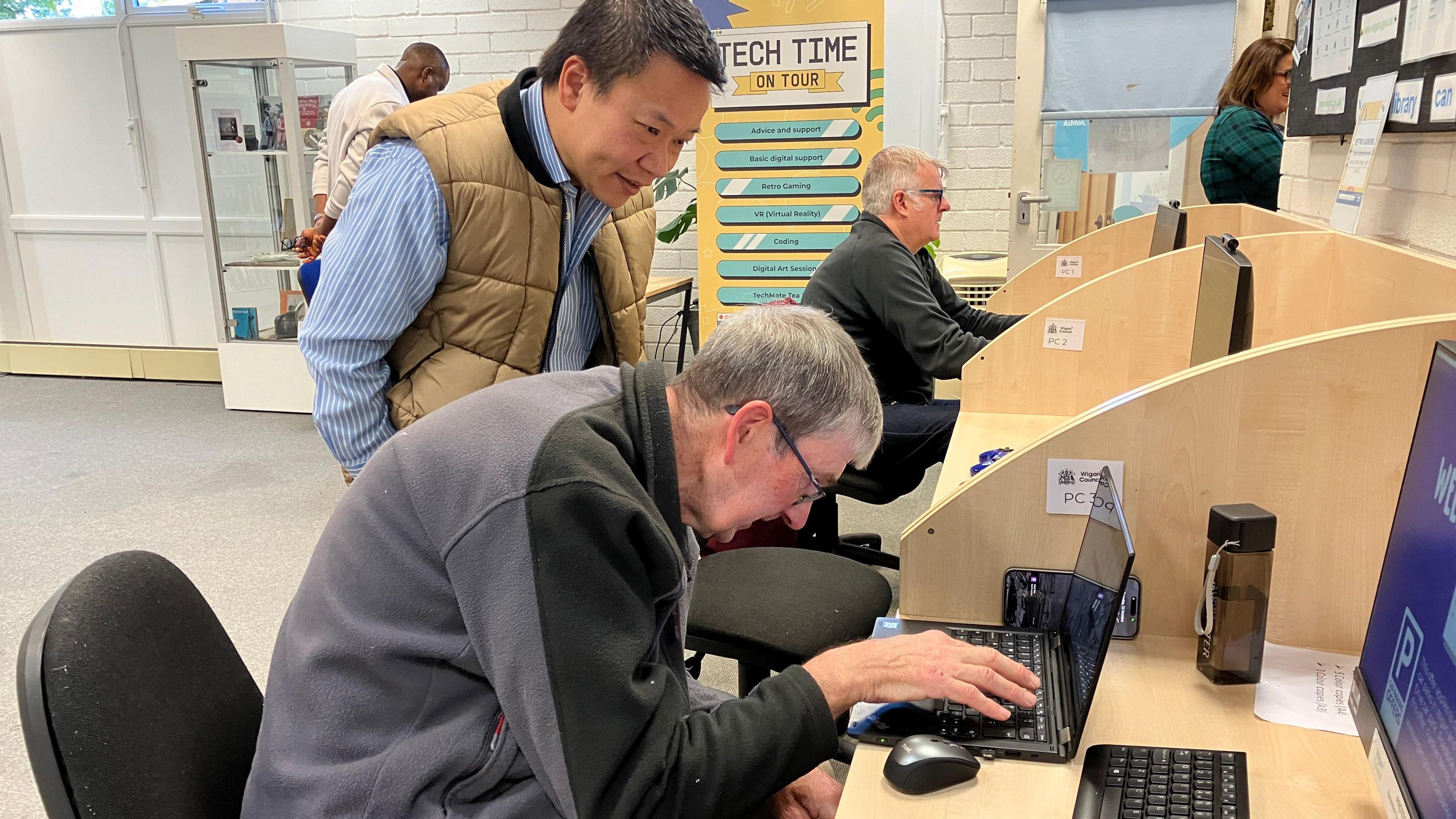 An older man sitting at a desk using a laptop.