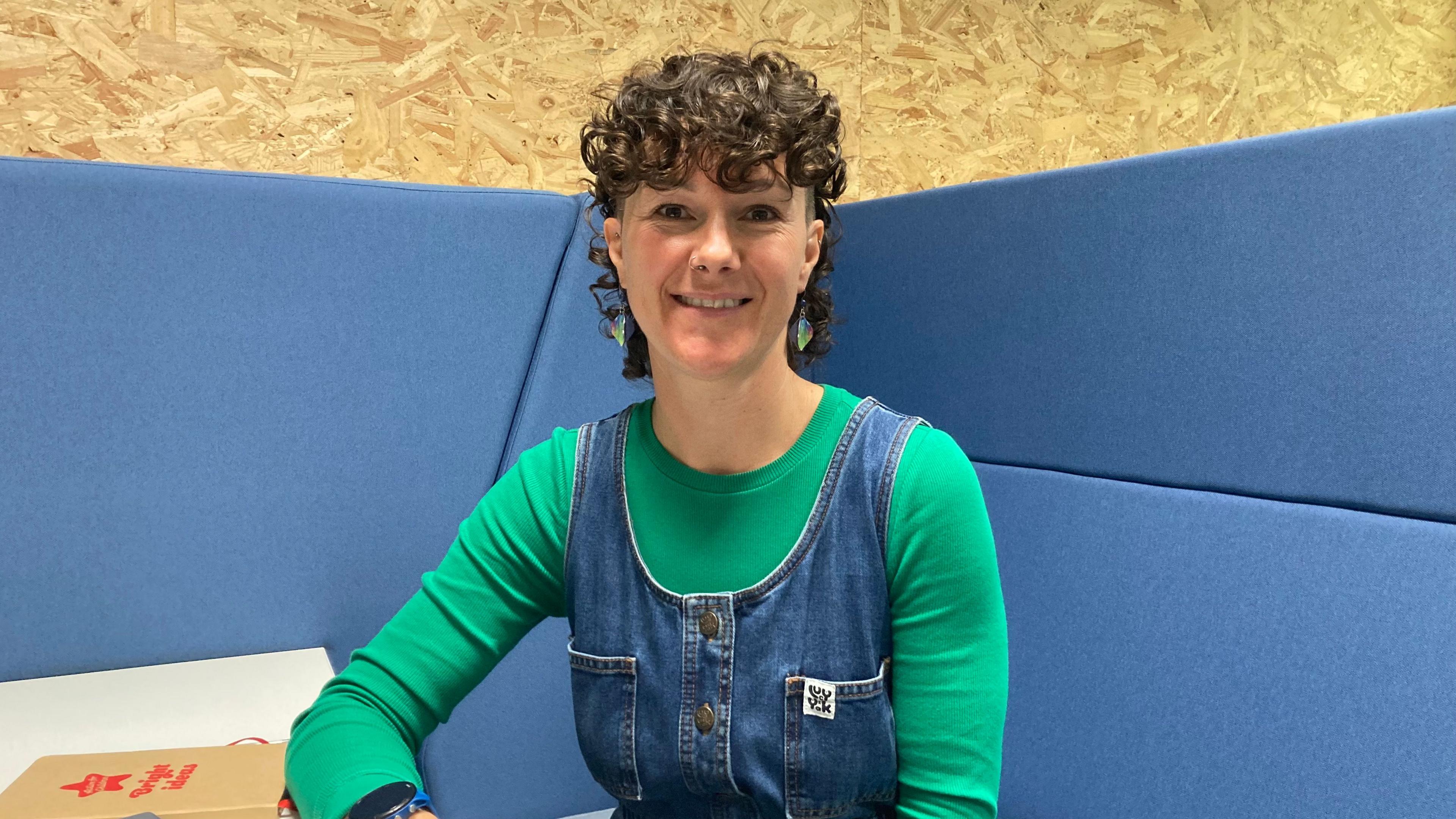 Deputy Tina Bury, President of the Committee for Employment and Social Security.
She is wearing a green top with denim dungarees over the top