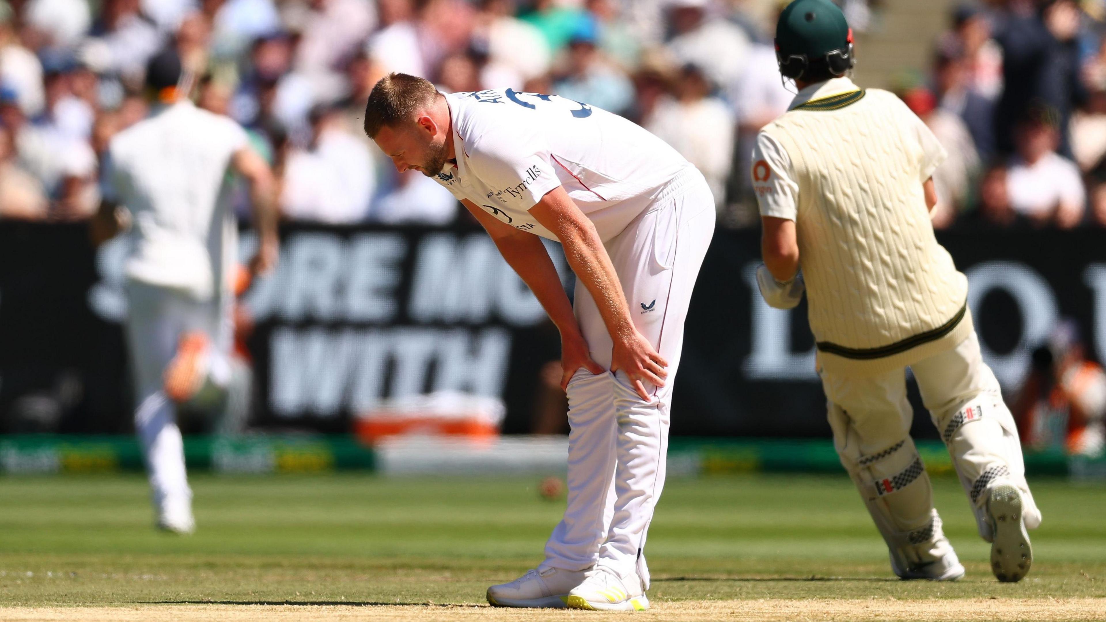 England bowler Gus Atkinson bends over to hold is legs with an apparent hamstring injury