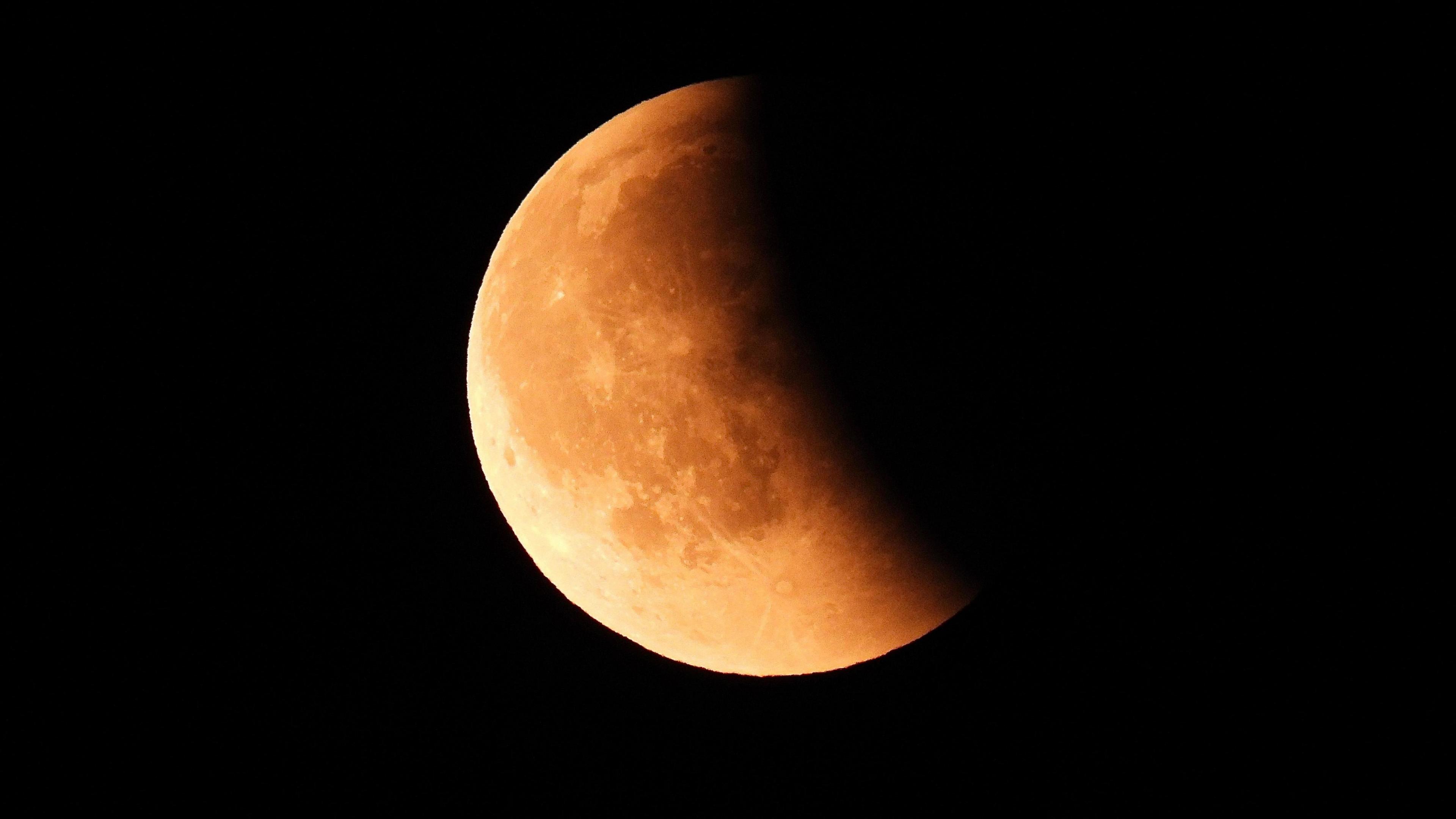 The moon with a red-orange tinge, partially in shadow