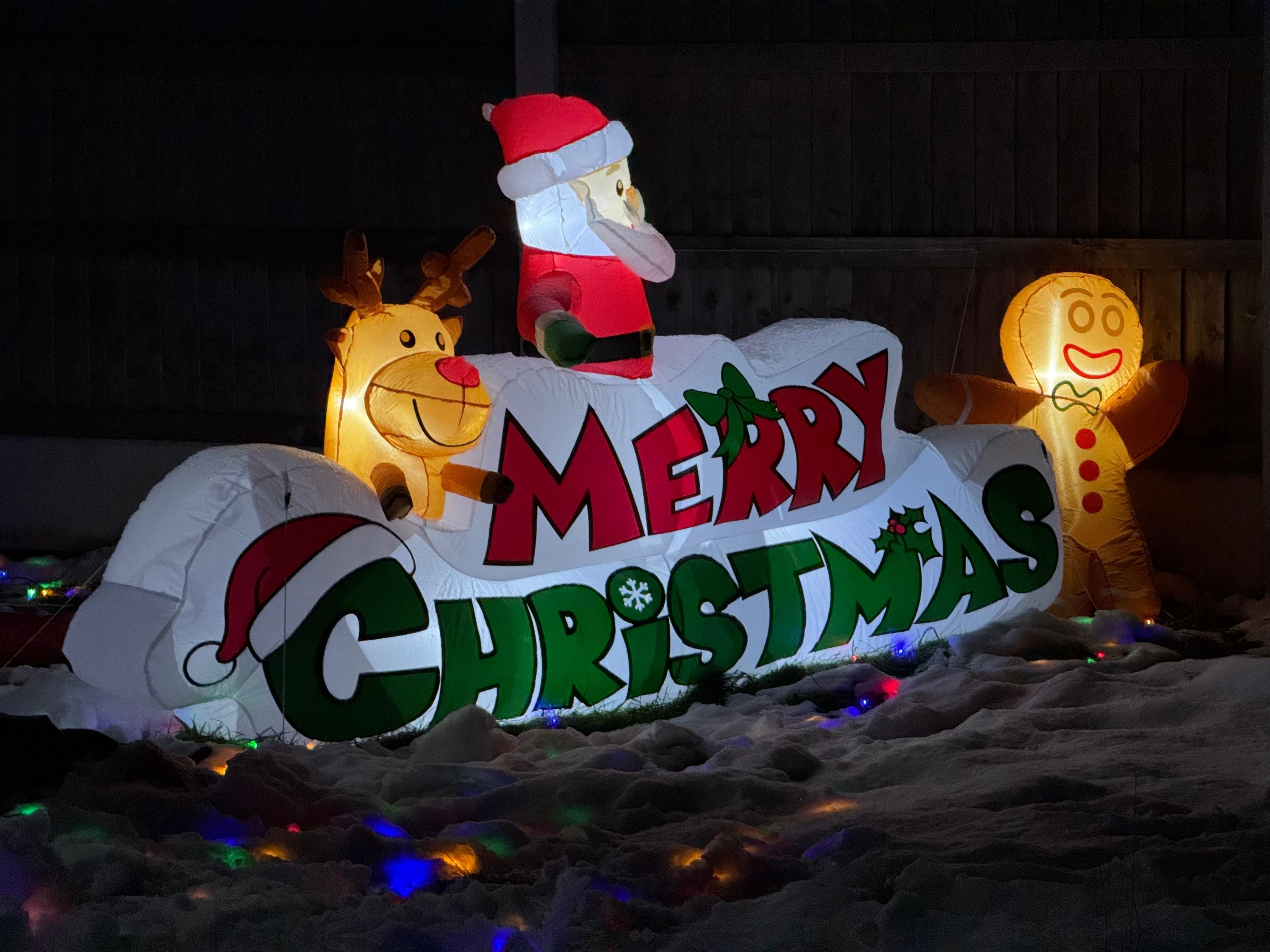 Close-up of an inflatable, illuminated Christmas decoration - featuring Father Christmas, a reindeer and a gingerbread man - in a garden