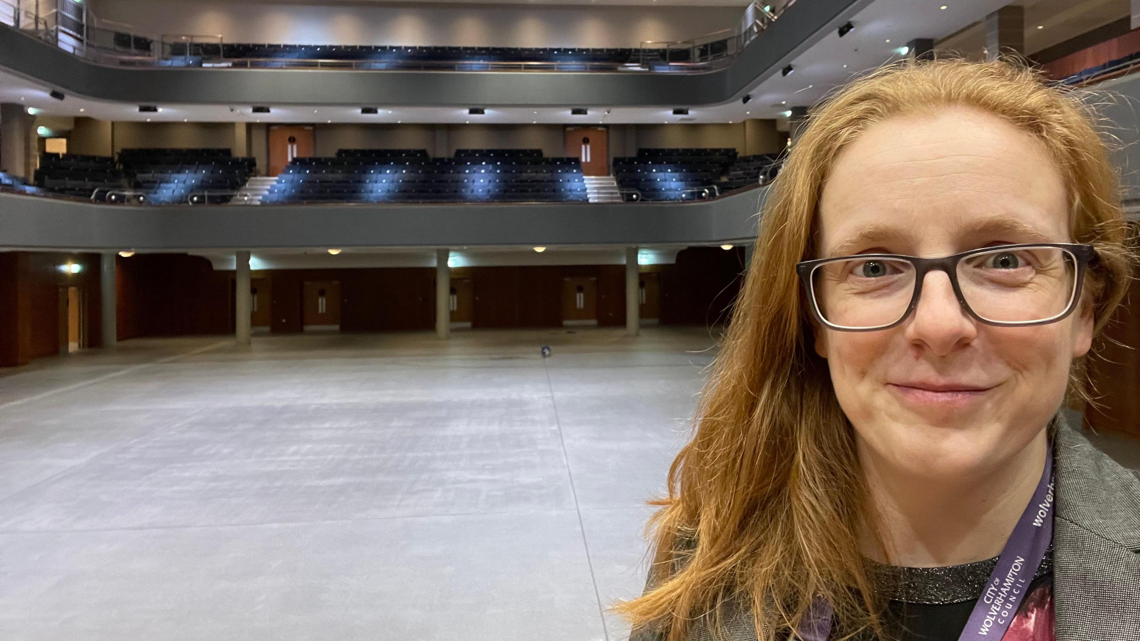 Crissie Rushton with red hair and glasses standing in an empty Wolverhampton entertainment venue