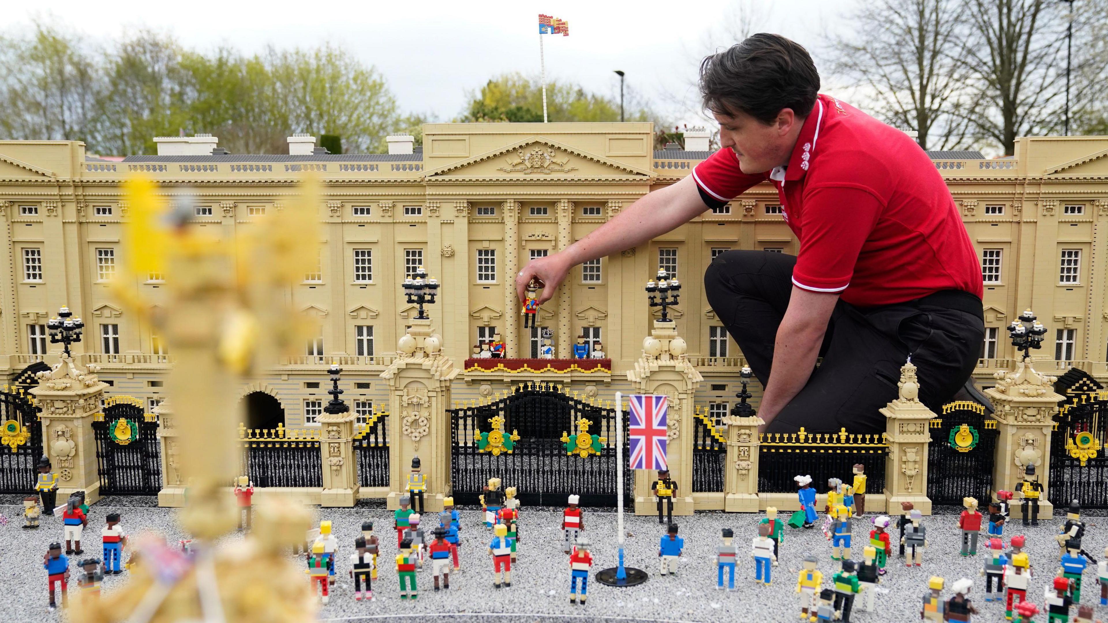 A worker at Legoland works on constructing a massive Buckingham Palace from bricks.