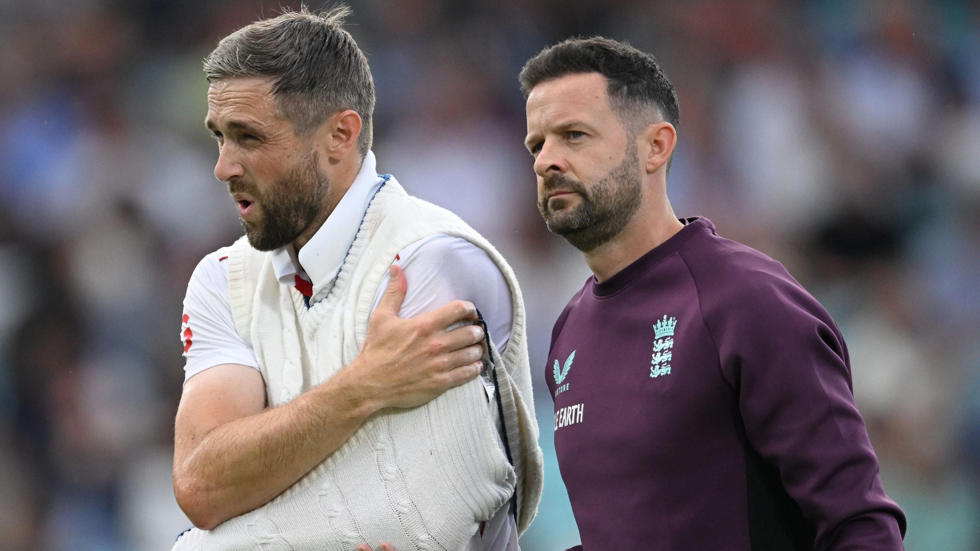 Chris Woakes walks off with his arm in a makeshift sling after suffering a shoulder injury