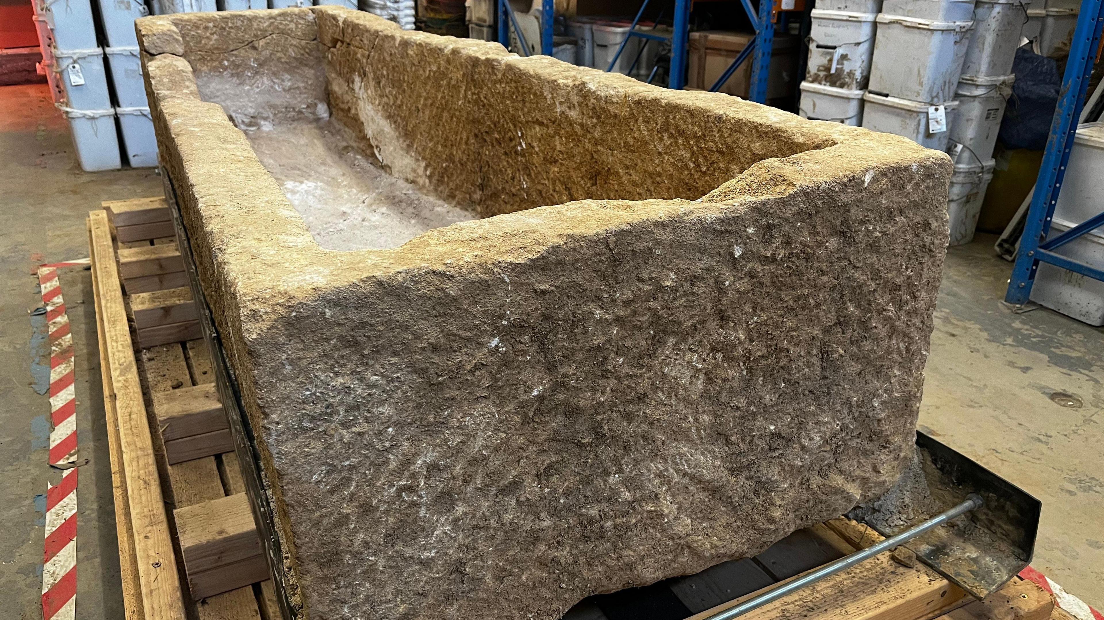 A large stone coffin in a archaeological storage area