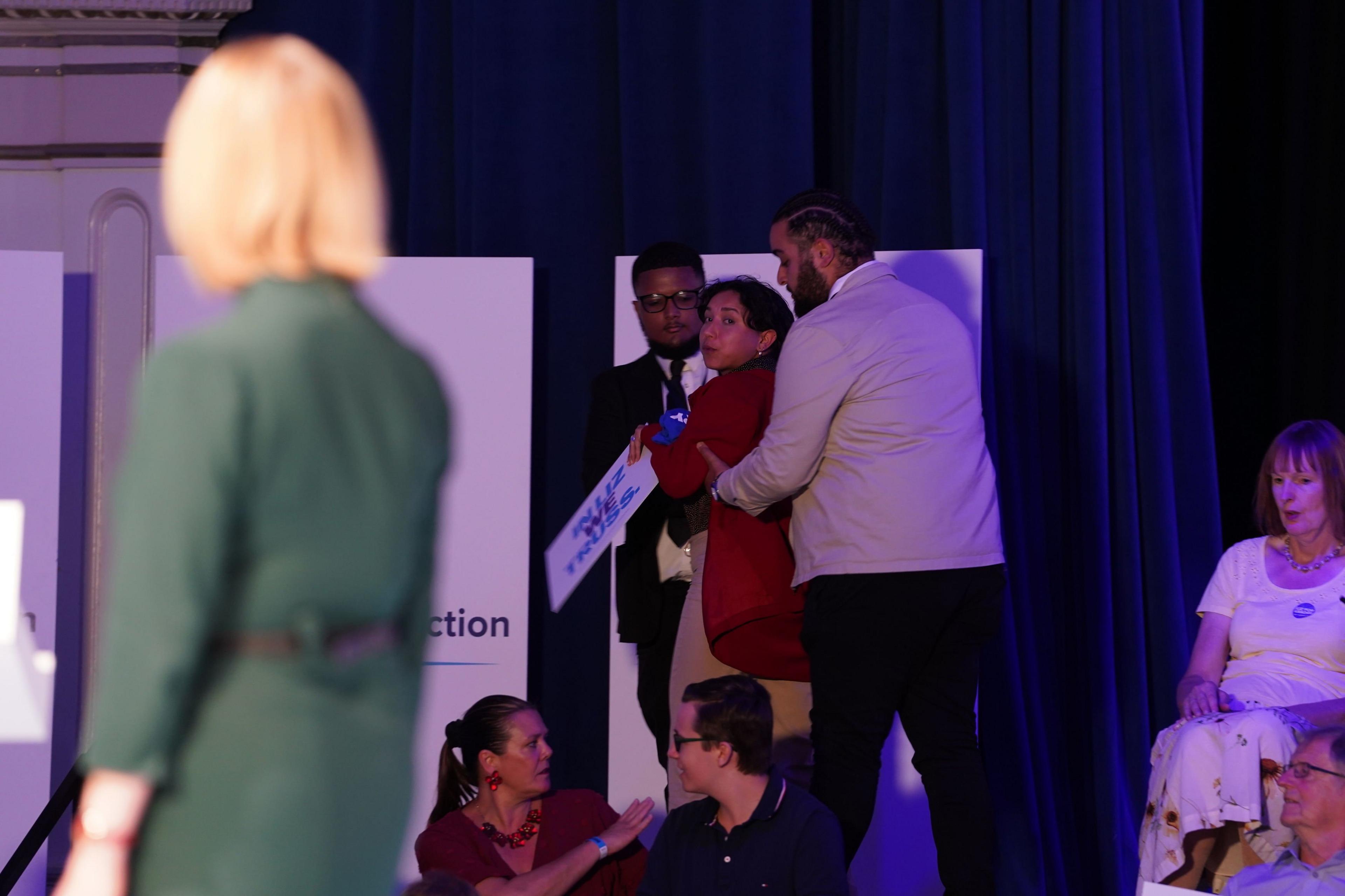 Liz Truss looks at a protestor being expelled from a hustings event