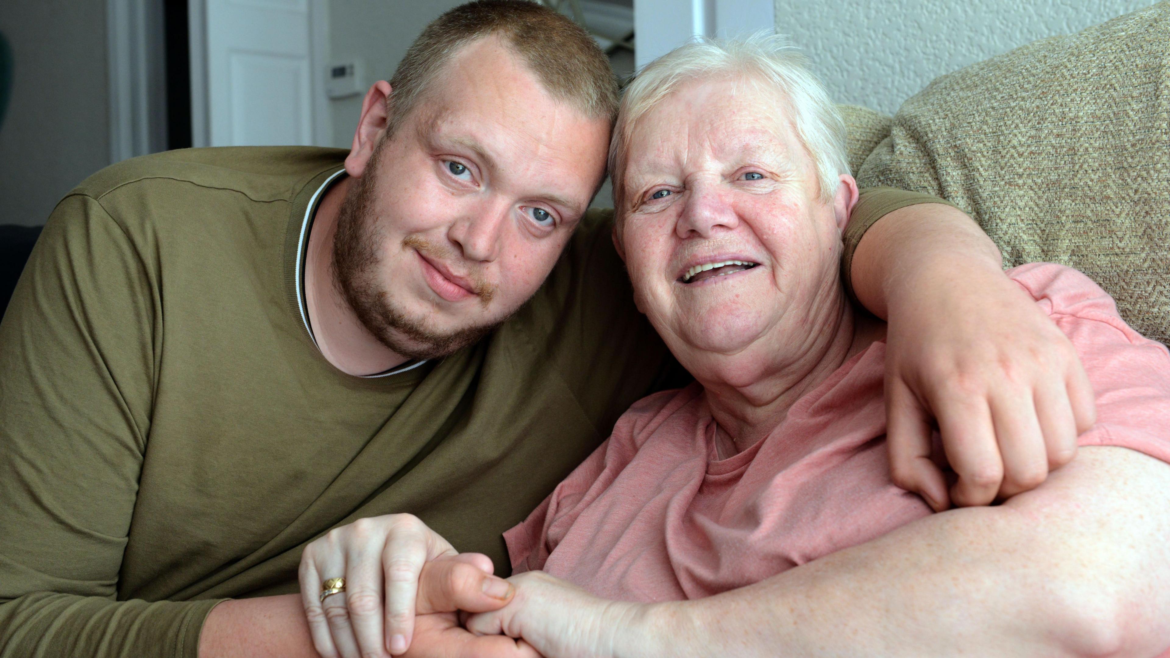 Robert Richardson sitting with his arm held around his mother Barbara. The two are holding hands.