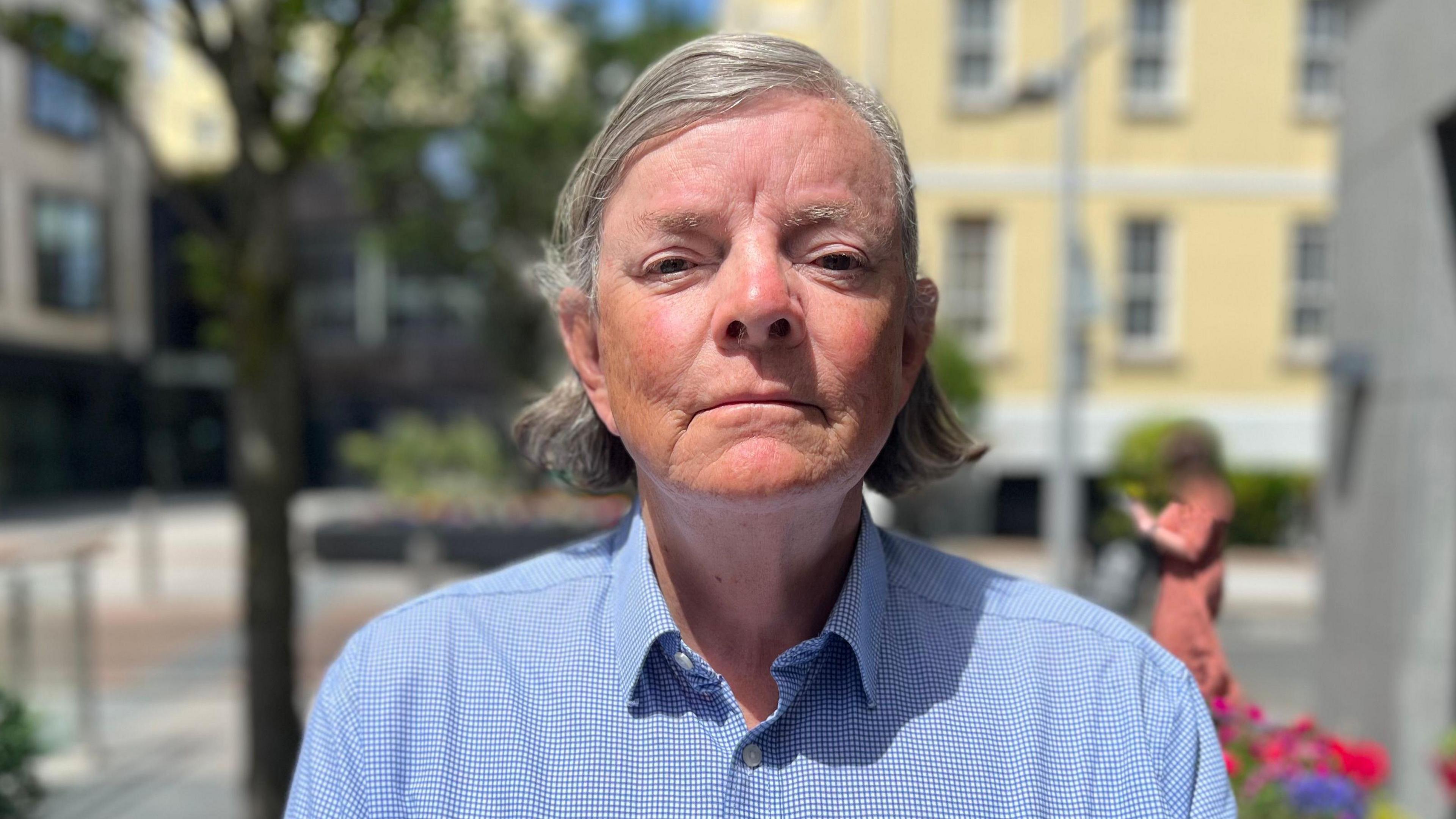 Deputy Charles Parkinson - A man with medium length grey hair, wearing a blue shirt. He's looking directly at the camera. 