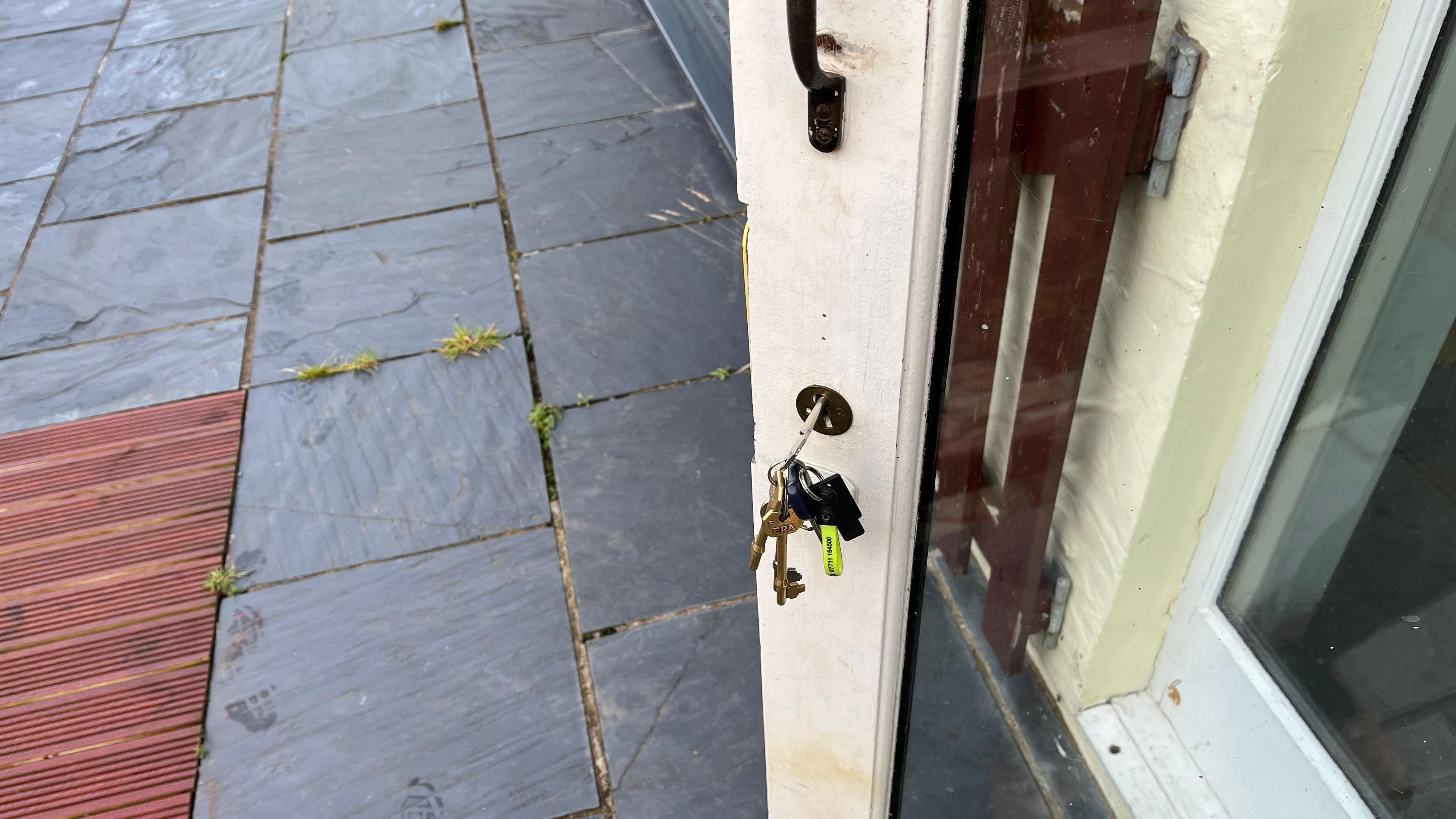 Glass door with white wooden frame and keys in lock