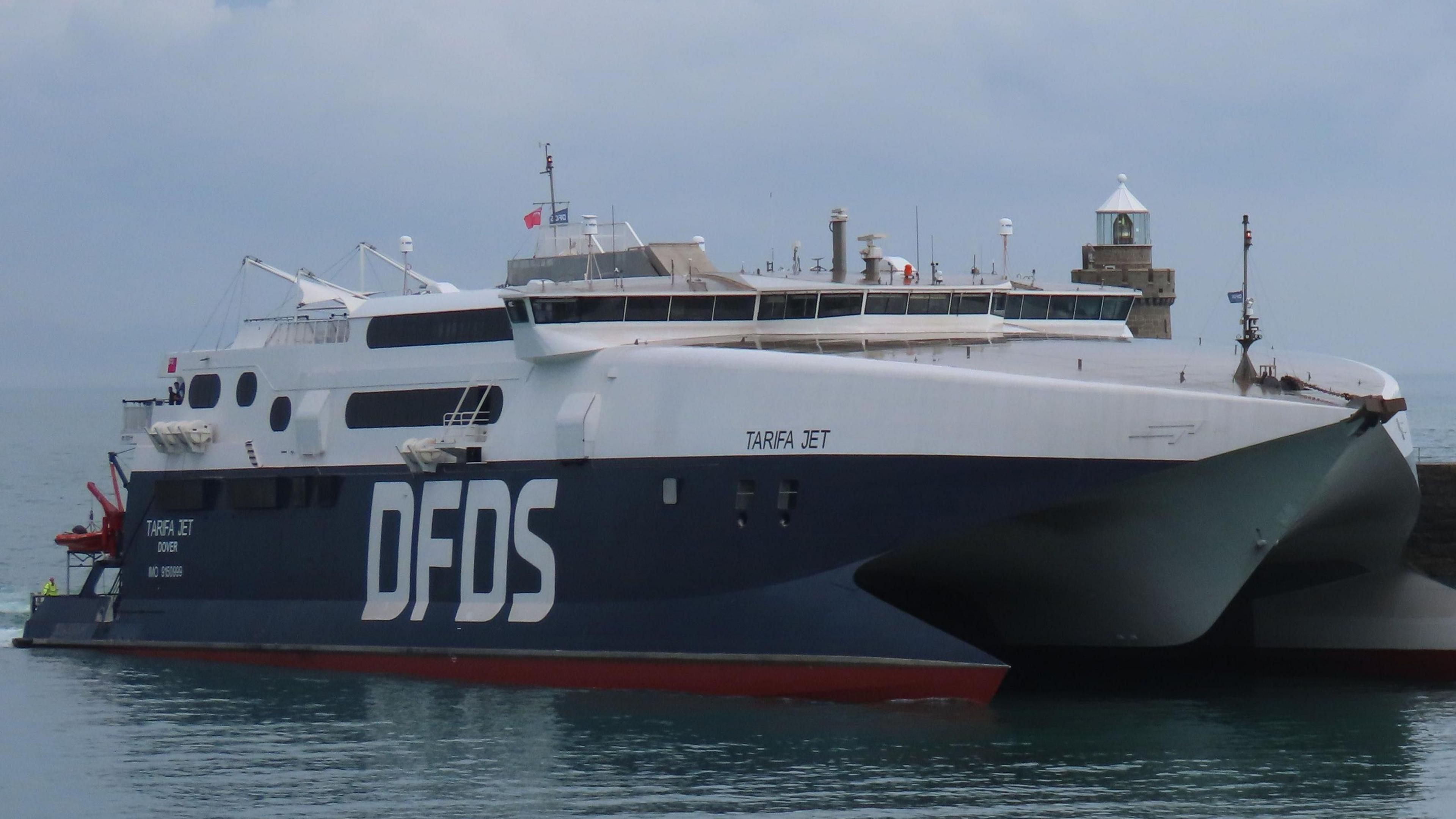 A picture of a large navy blue DFDS ferry. It is large with white font of the side saying DFDS.